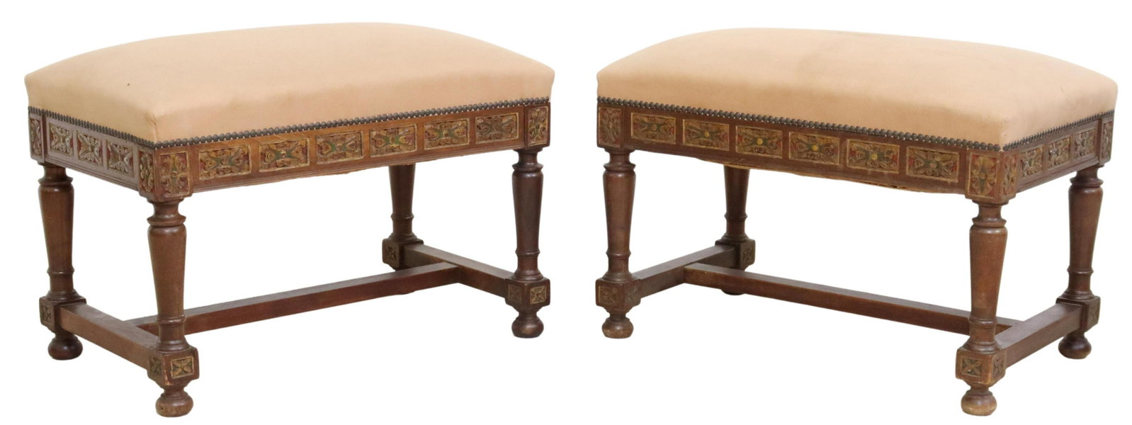 (2) SPANISH BAROQUE STYLE POLYCRHOME FOOTSTOOLS: (pair) Spanish Baroque style footstools, 19th c., in peach upholstery, with nailhead trim, carved polychrome floral border, rising on turned and tapered legs, joined with H-stretcher, ending on bun fe