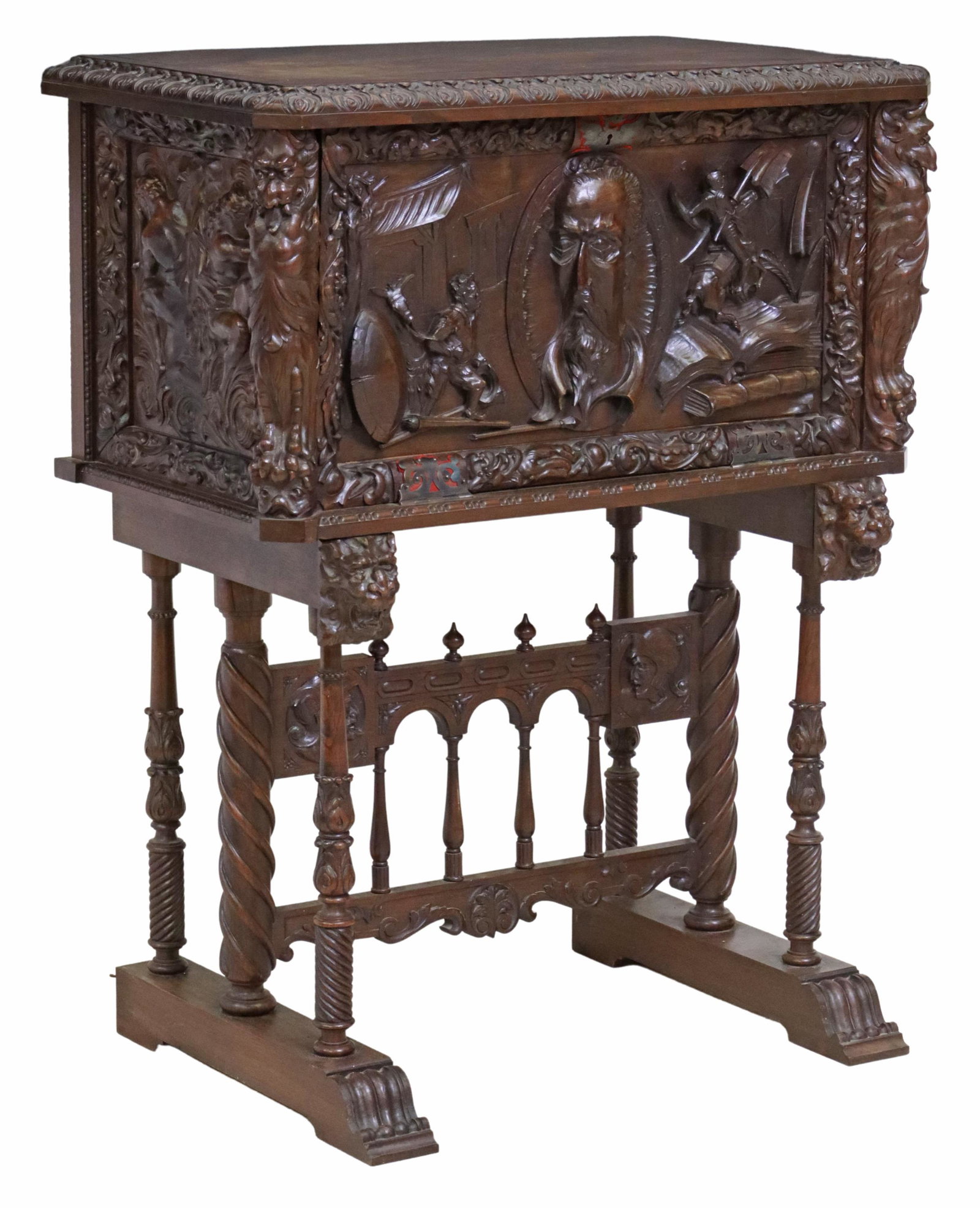 SPANISH FIGURAL CARVED WALNUT VARGUENO ON STAND: Spanish walnut bargueno/ vargueno, early 20th c., fall-front panel with carved portrait of Miguel de Cervantes, framed by scenes with Don Quixote and Sancho Panza, fitted interior with three small dra