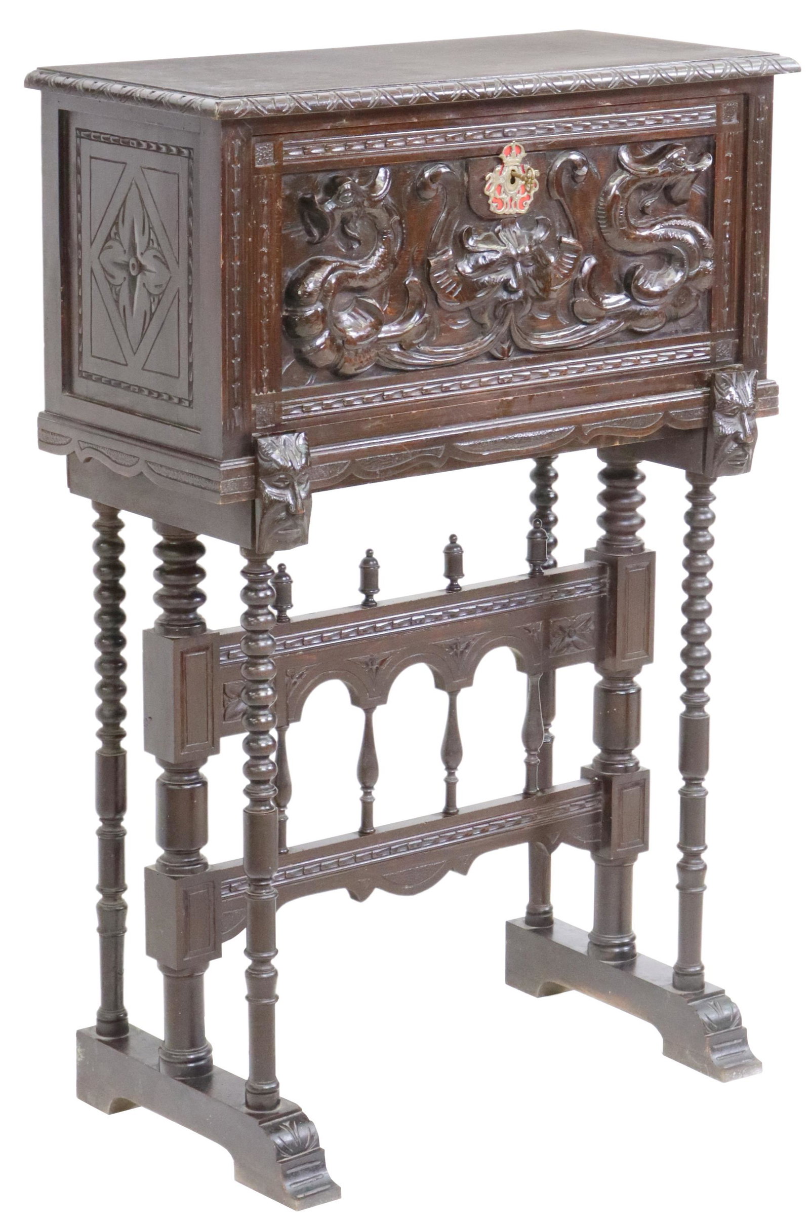 SPANISH RENAISSANCE REVIVAL VARGUENO ON STAND: Spanish Renaissance Revival bargueno/ vargueno, 19th c., having carved lunette border, over fall front door, faced with central grotesque mask issuing dragons, opening to shelved interior, rising on s