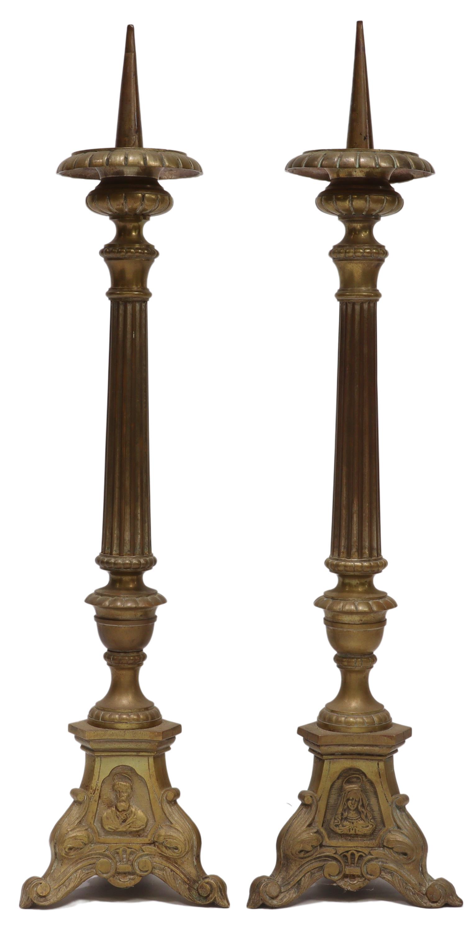 (2) CONTINENTAL BRASS CHURCH ALTAR CANDLE PRICKETS: (pair) Continental brass church altar candle prickets, late 19th c., ribbed and urn-form bobeche, over fluted standard, rising on tripodal base with ecclesiastical figural medallions, featuring Jesus 