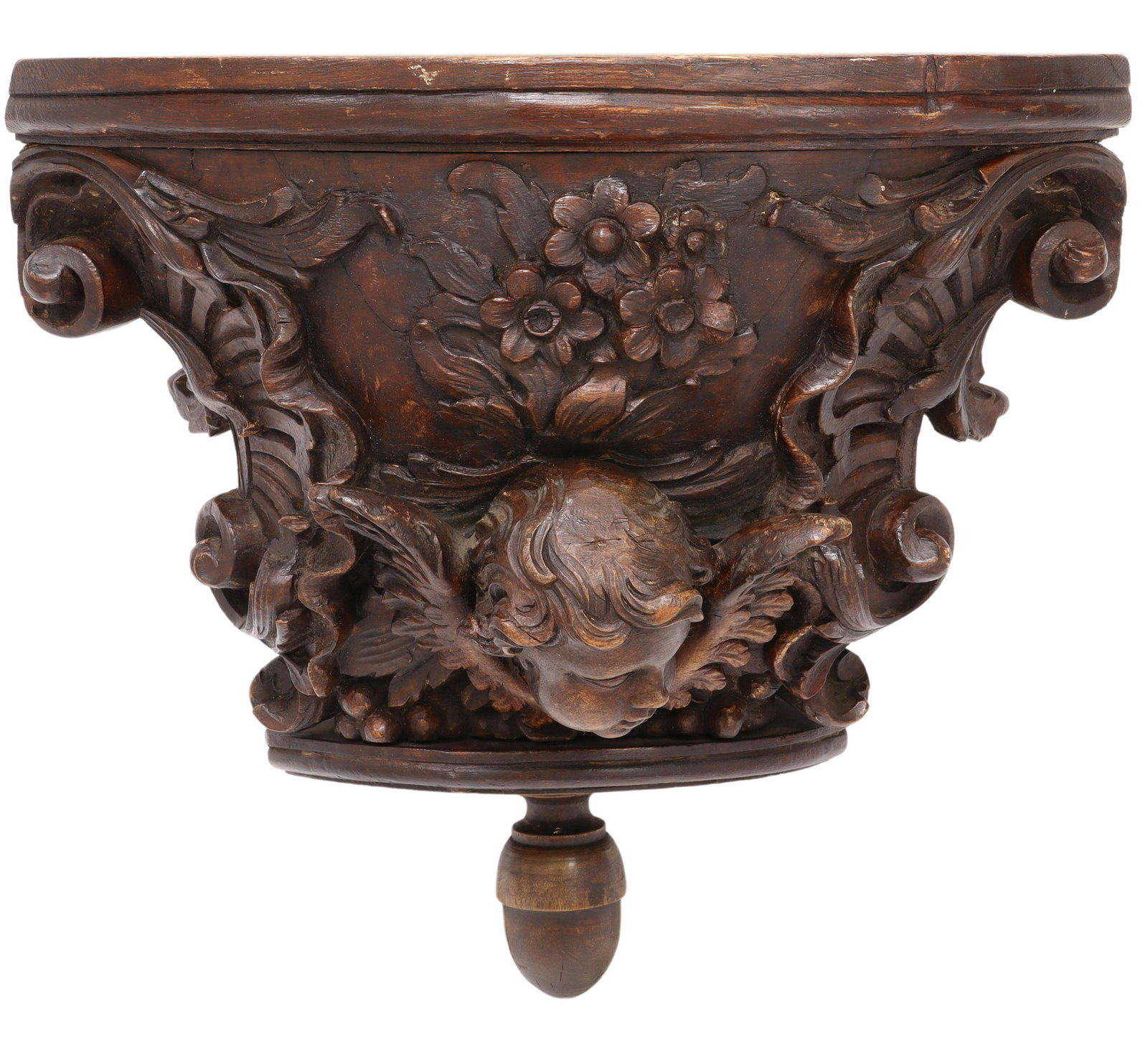 FRENCH CARVED CHERUB MASK CORBEL WALL BRACKET: French architectural carved corbel/ wall bracket, 18th/ 19th c., having rounded top, over central protruding winged cherub mask, flanked by large scrolling foliates, ending in turned acorn drop finial