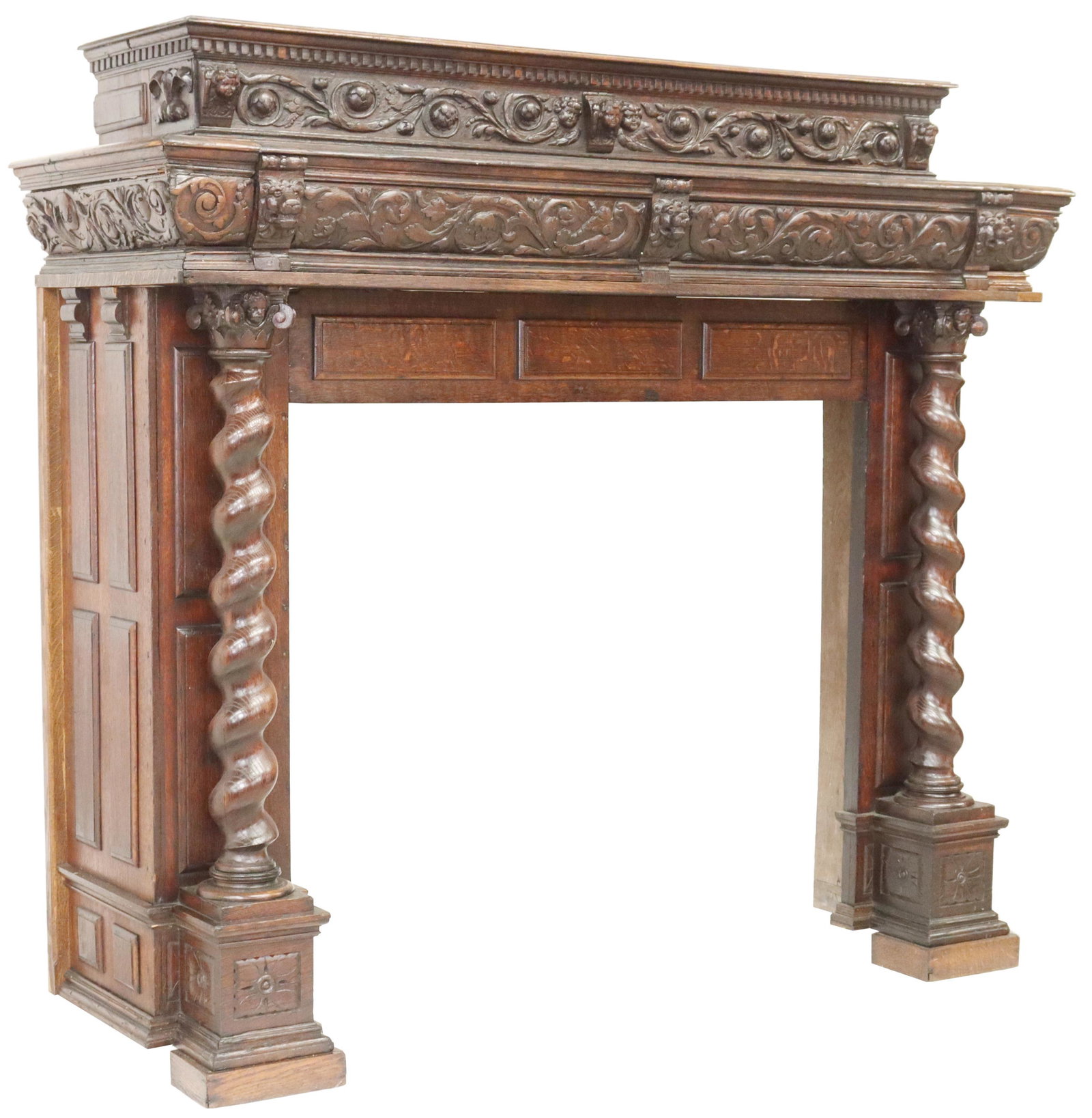 RENAISSANCE REVIVAL OAK FIREPLACE MANTEL SURROUND: Continental architectural Renaissance Revival oak fireplace mantel surround, having dentil trim, protruding cherub and lion masks throughout, with rinceau accents, paneled sides, rising on turned fron