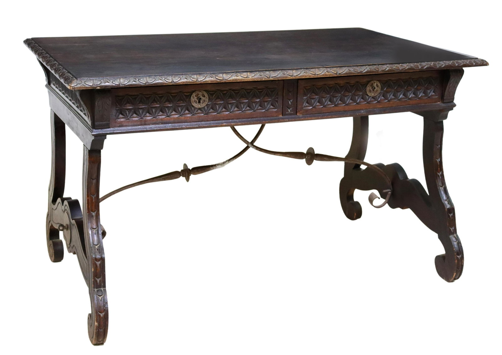 SPANISH BAROQUE STYLE CARVED WRITING DESK: Spanish Baroque style writing desk, late 19th/ early 20th c., carved apron with two frieze drawers, rising on scrolled ox yoke supports, joined by wrought iron cross stretchers, stretcher broken, in n