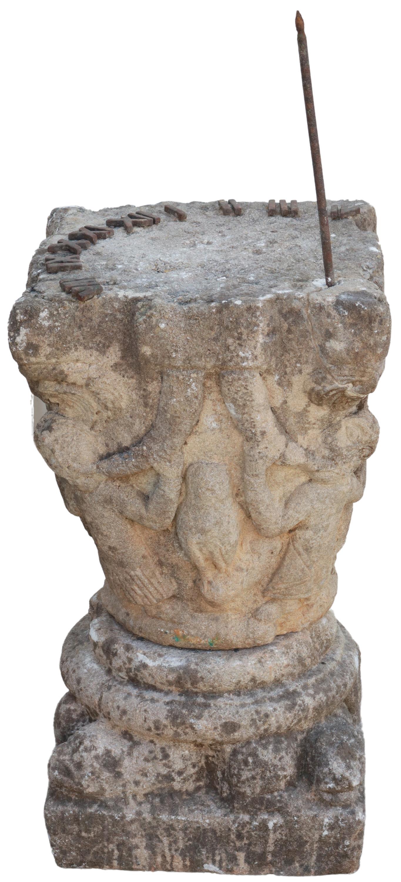 CARVED STONE FIGURAL CAPITAL-FORM SUNDIAL: Carved stone capital-form sundial, iron roman numerals and gnomon to top, over figural carved standard, rising on separate shaped square base, lacking numerals V & VI, approx 23"h, 13"sq (not includin