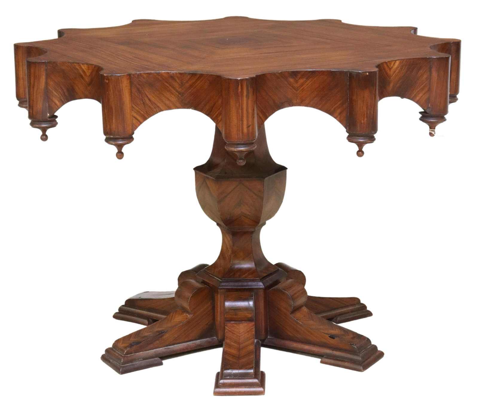 AMERICAN ROSEWOOD SCALLOPED APRON CENTER TABLE: American rosewood center table, early 20th c., having shaped matched-veneer top, scalloped apron, with drop finials, rising on baluster-form standard, ending on six bridge feet, approx 30.75"h, 43.5"d