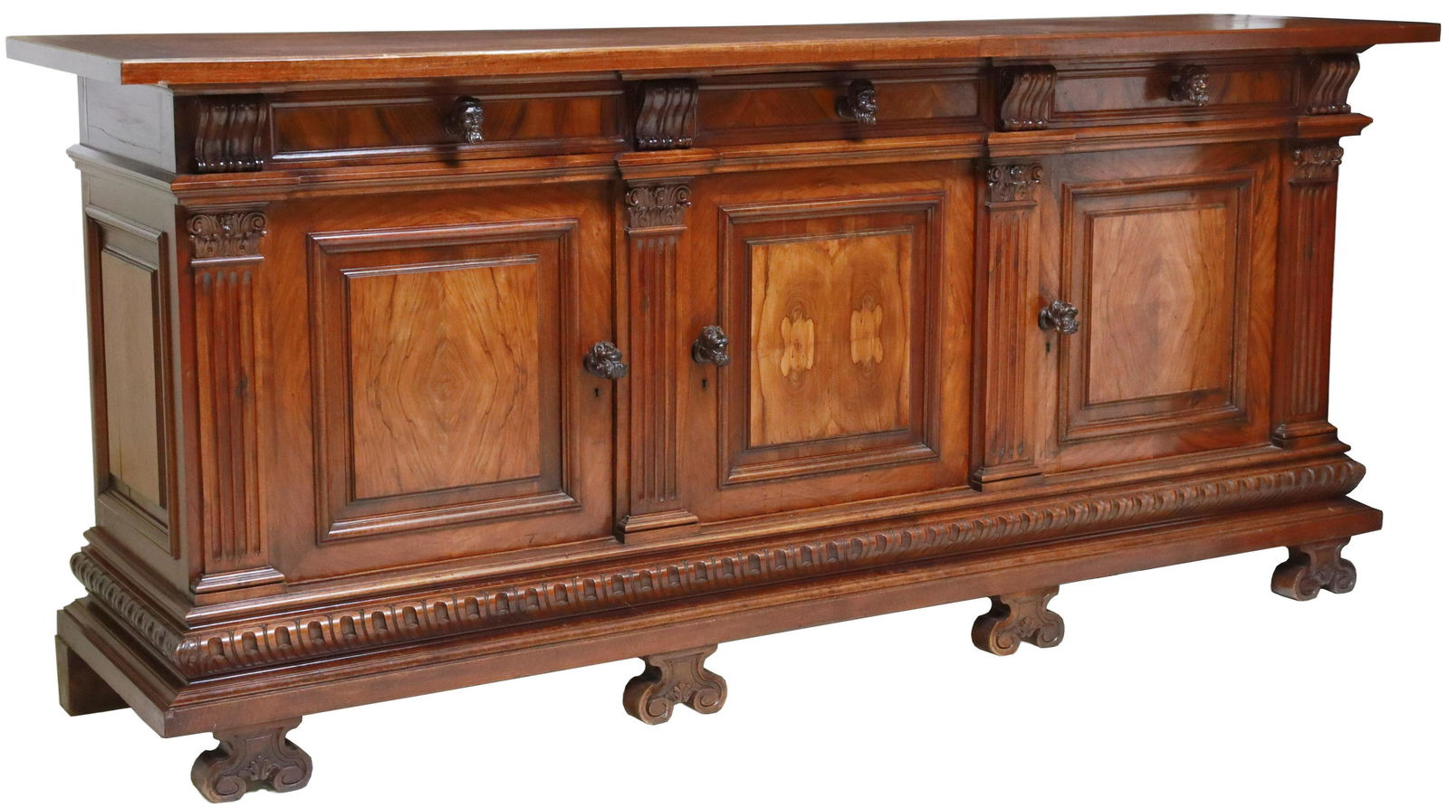ITALIAN RENAISSANCE REVIVAL WALNUT SIDEBOARD: Italian Renaissance Revival carved walnut sideboard, A. Brizzolara & Figli, Chiavari, early 20th c., having three drawers, over three paneled cabinet doors, flanked by fluted pilasters, figural mask d
