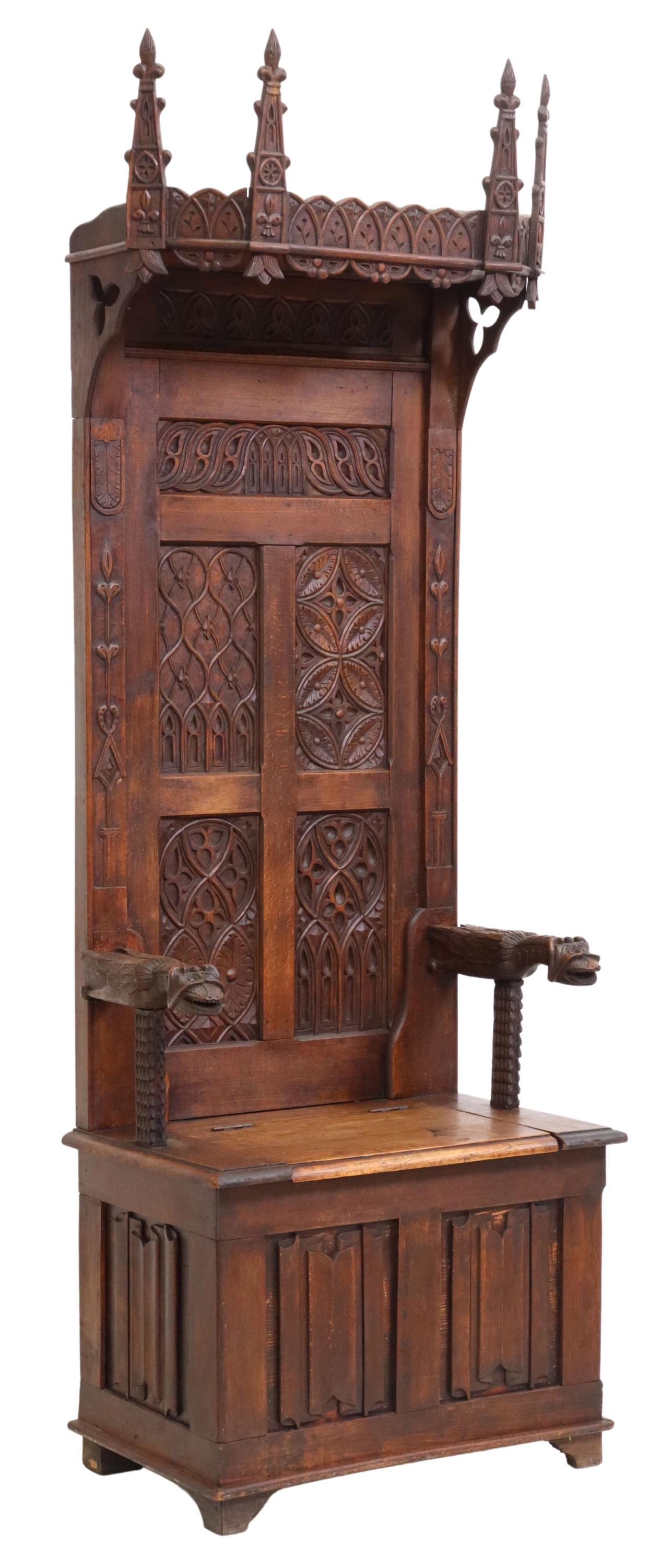 FRENCH GOTHIC REVIVAL OAK THRONE/ HALL CHAIR: French Gothic Revival oak throne/ hall chair, 19th c., spire finial crest, back with various carved tracery designs, over mythical beast handholds, hinged seat opening to storage interior, above lower
