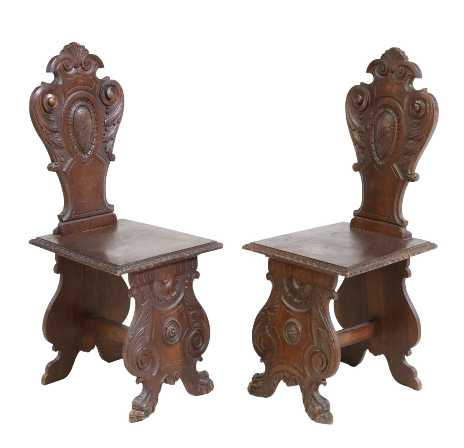 (2) ITALIAN RENAISSANCE REVIVAL WALNUT HALL CHAIRS: (pair) Italian Renaissance Revival walnut hall chairs, 19th c., carved shell crest, over shield-form back, seat with running ornamentation border, rising on foliated scroll supports, ending on paw fee