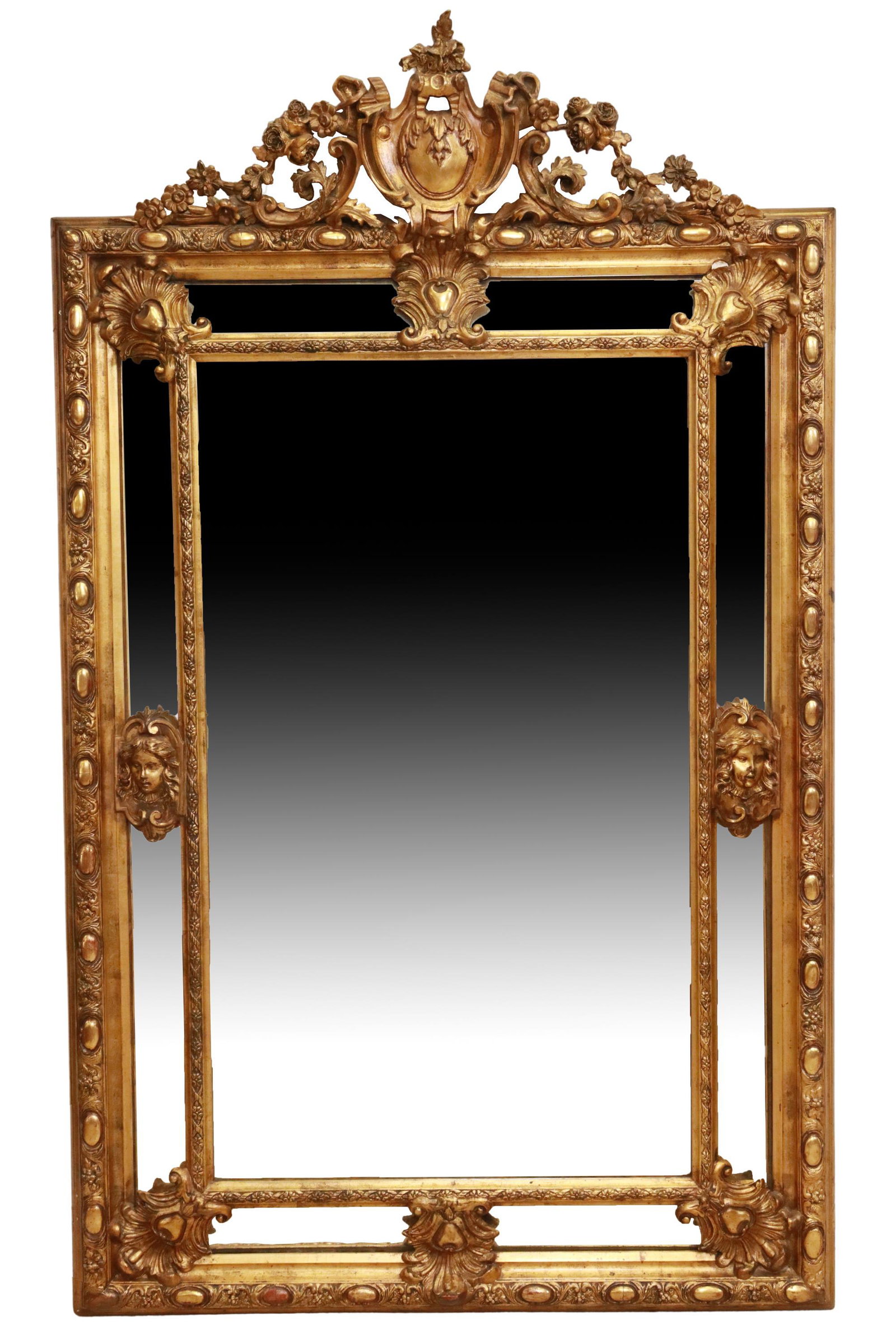 LOUIS XVI STYLE GILTWOOD CUSHION WALL MIRROR, 77"H: Continental Louis XVI style giltwood and gesso cushion wall mirror, late 19th c., having shield crest flanked by scrolled foliates and floral motifs, over cushion frame with running ornamentation, fig