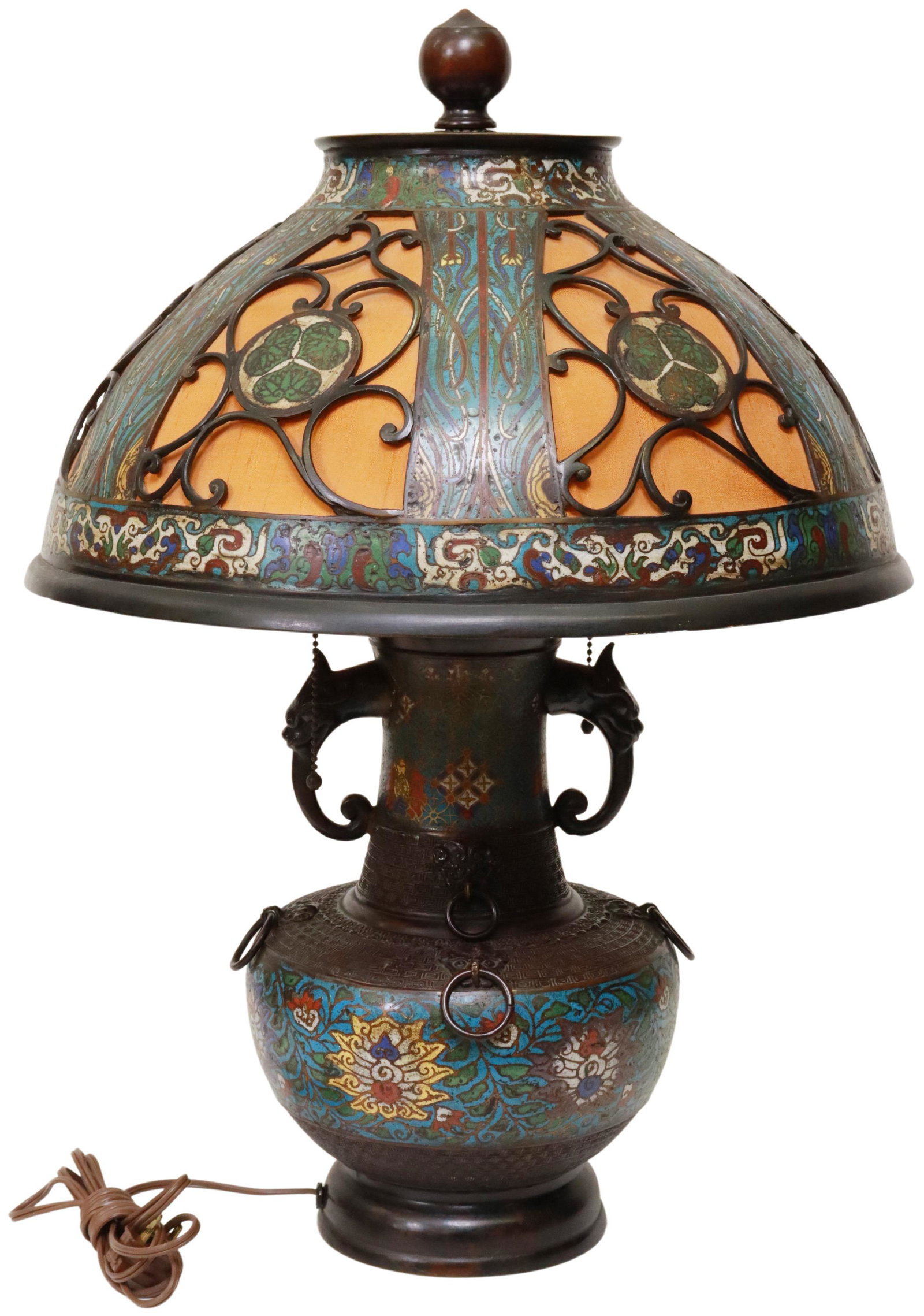 LARGE CHAMPLEVE ENAMEL 2-LT TABLE LAMP & SHADE: Champleve enamel urn-form two-light table lamp, pierced openwork shade, revealing fabric interior lining, over dragon mask handles, urn-form base adorned with bronze rings, approx 24.7"h, 17.5"diam, 2