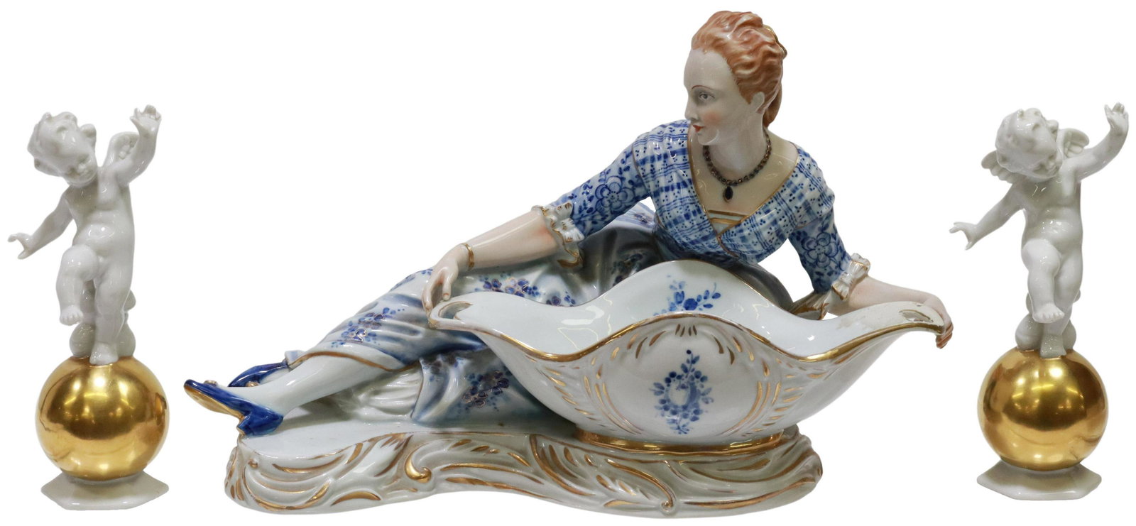 (3) CONTINENTAL SWEETMEAT DISH & PUTTI FIGURES: (lot of 3) Continental porcelain figures, including: (1) Capodimonte figural sweetmeat dish, reclining female figure supporting a handled bowl, blue underglaze crowned N mark underfoot, professional r