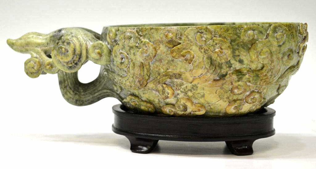 SUBSTANTIAL CHINESE CARVED NEPHRITE LIBATION CUP: Substantial Chinese nephrite libation cup carved to the exterior with billowing clouds, one of which forms the loop handle, portions of the russet and yellow inclusions incorporated into the design of