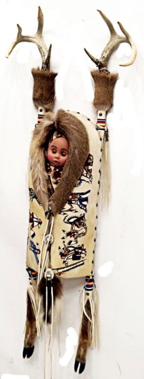 AMERICAN INDIAN CRADLE BOARD, DEER HIDE, ANTLERS: Native American made cradleboard, purchased 2004 from artist Velsworth Hawk (Crow, Ft. Thompson, South Dakota), the board topped with two 4 point deer antlers at each side, multi-color bead decoration