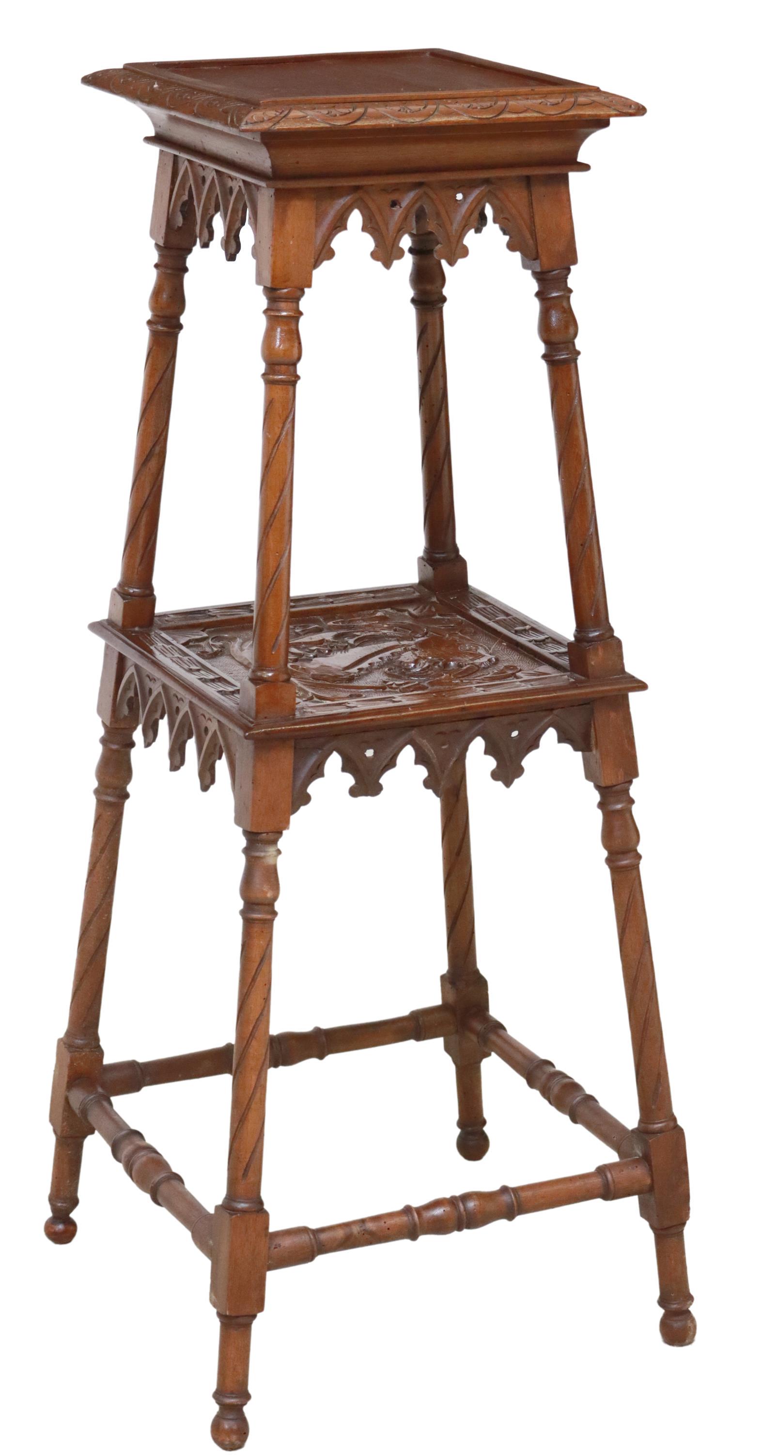 GOTHIC REVIVAL CARVED WALNUT PLANT STAND: Gothic Revival walnut plant stand, late 19th c., top shelf with lunette border, trefoil arcaded trim, over medial foliate carved shelf, rising on turned stretcher-joined supports, ending on bun feet, 