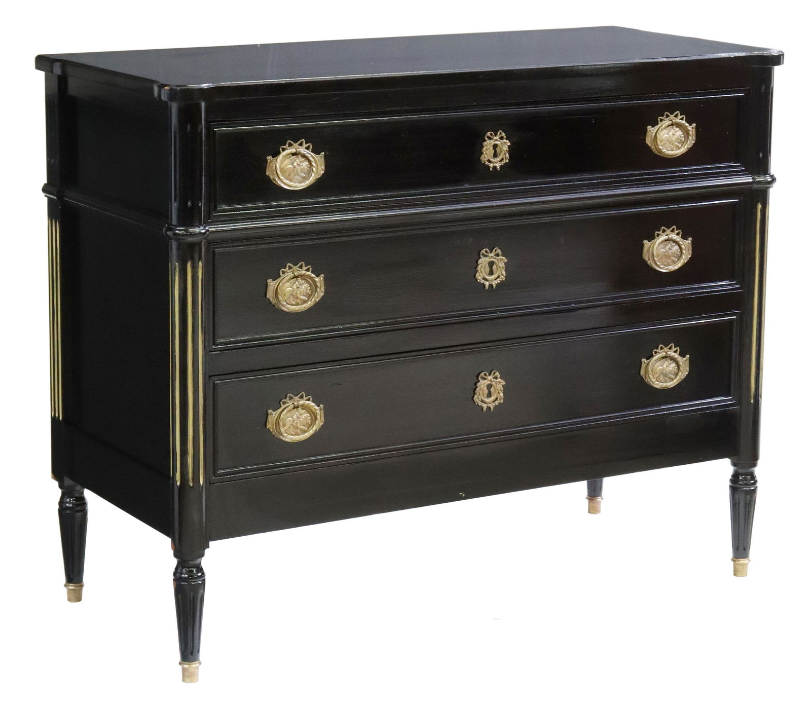 FRENCH LOUIS XVI STYLE EBONIZED COMMODE: French Louis XVI style ebonized commode, 20th c., fitted with three drawers, having decorative gilt metal pulls, flanked by fluted side supports, rising on tapered legs, ending on capped feet, approx