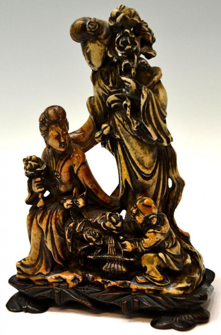 CHINESE HARDSTONE FIGURAL GROUP SCULPTURE: Chinese pierce carved stone figural group, late 19thc., two female figures, one standing, one seated, receiving flowers from a kneeling man who is removing them from a basket, signed in two places on