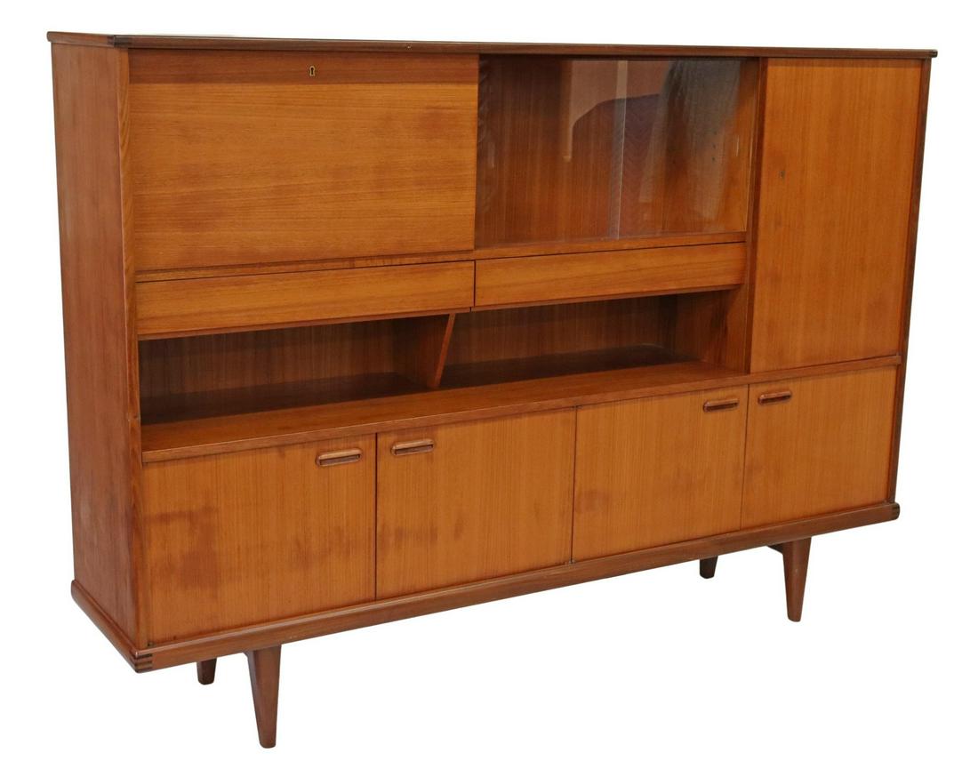 MID-CENTURY MODERN TEAK SIDEBOARD: Mid-century modern teak sideboard, c.1960s, fall front cabinet, dual sliding glass doors, tall side cabinet, two drawers with inserts for flatware, open shelves, over four cabinet doors, rising on tap