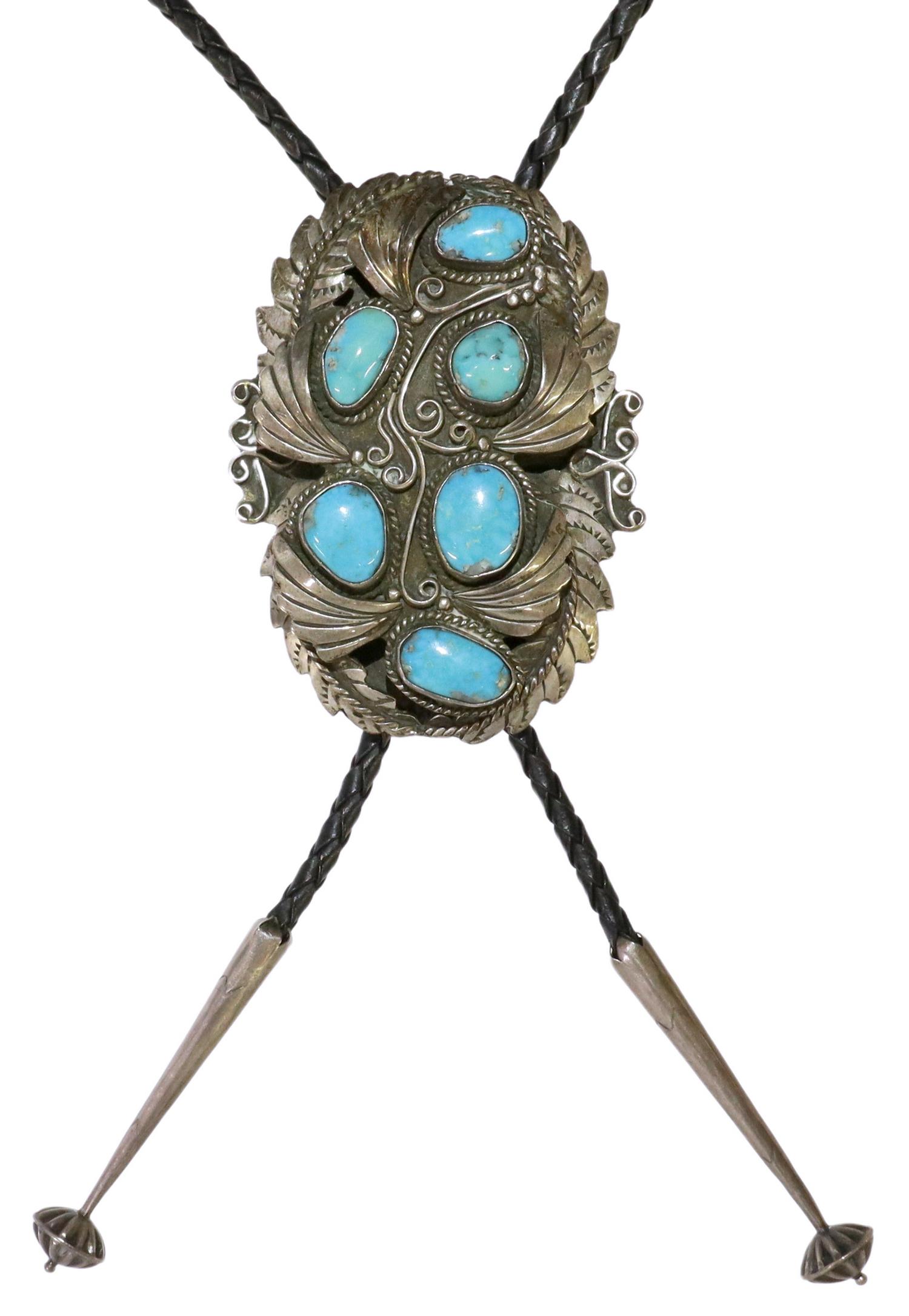 JUSTIN MORRIS NAVAJO SILVER & TURQUOISE BOLO TIE: Native American silver (content unknown) bolo tie, signed Justin Morris (Navajo/ Dine, 20th c.), feather design set with turquoise cabochons, silver bolo tips, on braided black leather cord, bolo orna