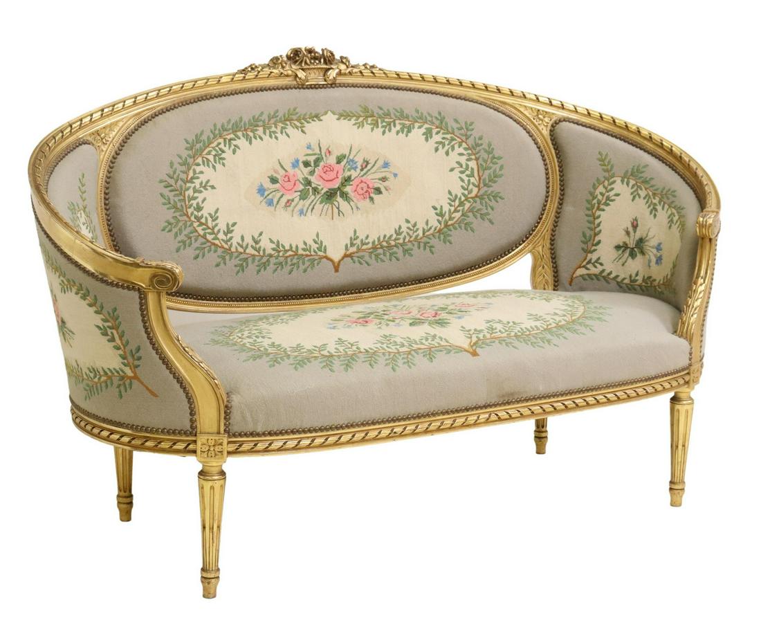 FRENCH LOUIS XVI STYLE GILTWOOD NEEDLEPOINT SETTEE: French Louis XVI style giltwood settee, 20thc., having floral crest, over oval back with ribbon twist molding, scrolled handholds, floral needlepoint upholstery, nailhead trim, rising on fluted tapere