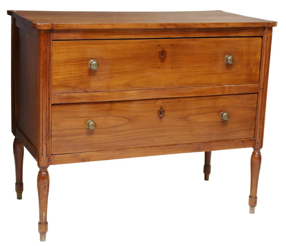 NEOCLASSICAL STYLE TWO-DRAWER COMMODE: Neoclassical style fruitwood two drawer commode, 20th c., two drawers feature shield form escutcheons, flanked by fluted carving, on turned legs, approx 35"h, 42.5"w, 21"d Start Price: $400.00