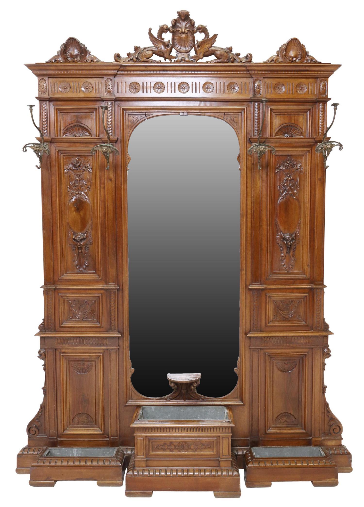 ITALIAN RENAISSANCE REVIVAL WALNUT HALL TREE: Italian Renaissance Revival walnut hall tree, 19th c., having dragon and shell crest, molded cornice, over four mythical beast hooks, back carved throughout with running ornamentation, central beveled