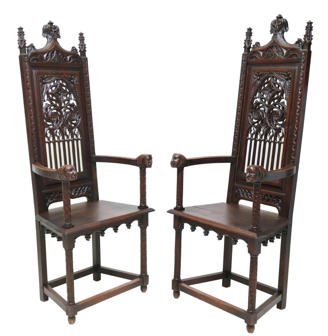 (2) FRENCH GOTHIC REVIVAL OAK THRONE ARMCHAIRS: (pair) French Gothic Revival oak throne armchairs, 19th c., having foliate crest, pierced tracery back, figural mask handholds, rising on carved legs, joined with box stretcher, ending on turned feet,