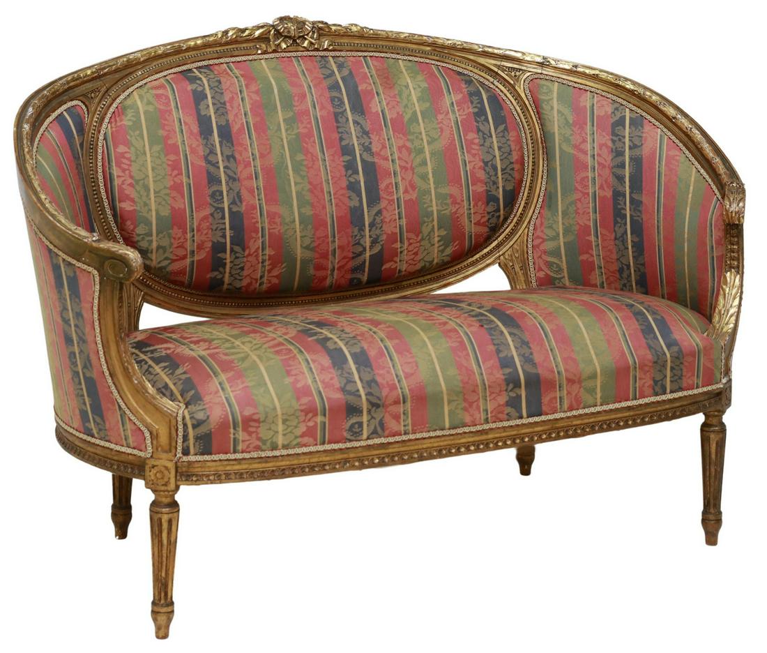 FRENCH LOUIS XVI STYLE GILTWOOD UPHOLSTERED SETTEE: French Louis XVI style giltwood settee, 20thc.., having ribbon crest and foliate molding, striped floral upholstery, ribbon trim, rising on fluted tapered legs, ending in arrow feet, approx 35"h, 50"w