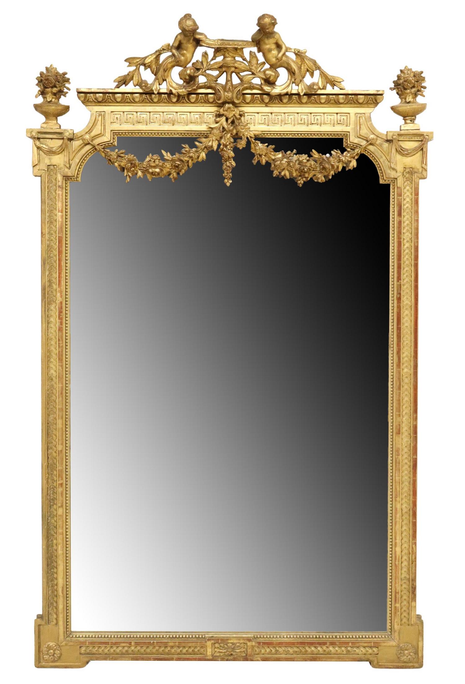 FRENCH LOUIS XVI STYLE GILTWOOD PUTTI WALL MIRROR: French Louis XVI style giltwood wall mirror, late 19th c., having figural putti crest with scrolled foliates and floral swag, flanked by floral urn finials, over molded frame with beaded trim, encasin