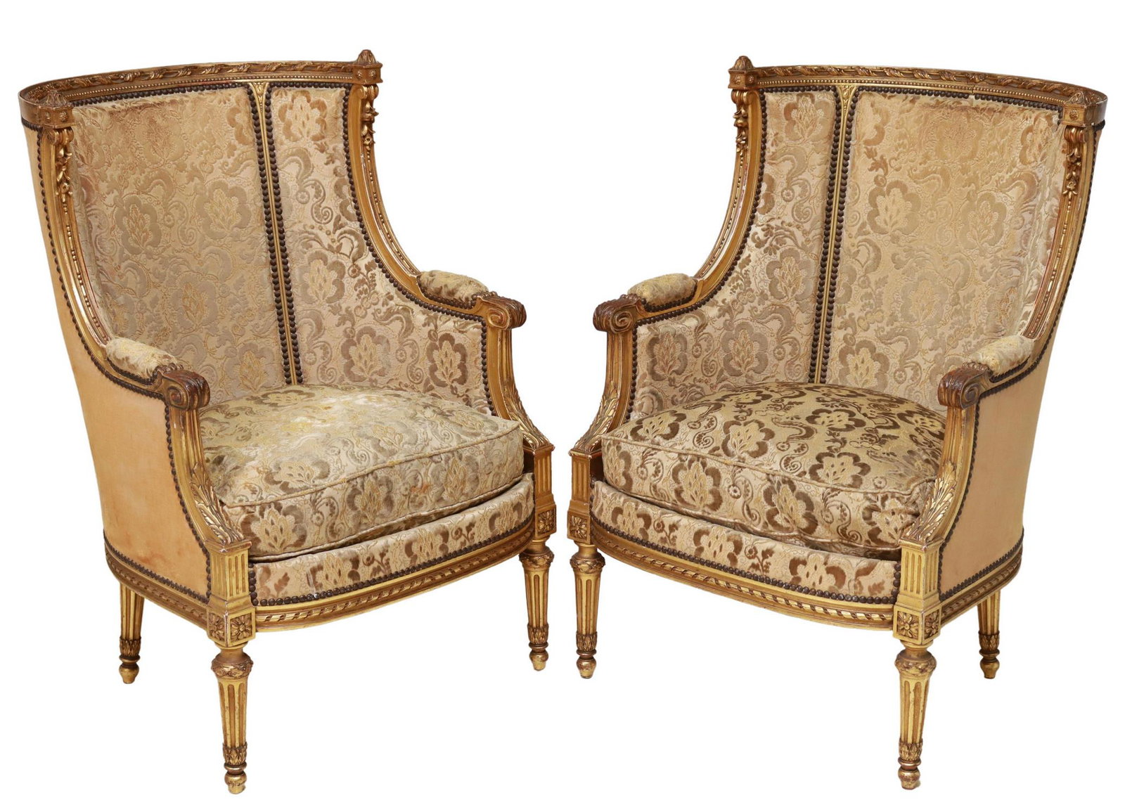 (2) FRENCH LOUIS XVI STYLE GILTWOOD BERGERES: (pair) French Louis XVI style giltwood armchairs, late 19th c., frame with foliate, beaded, and ribbon twist molding, enclosed curved back, loose seat cushion, rising on tapering fluted legs, wear to 