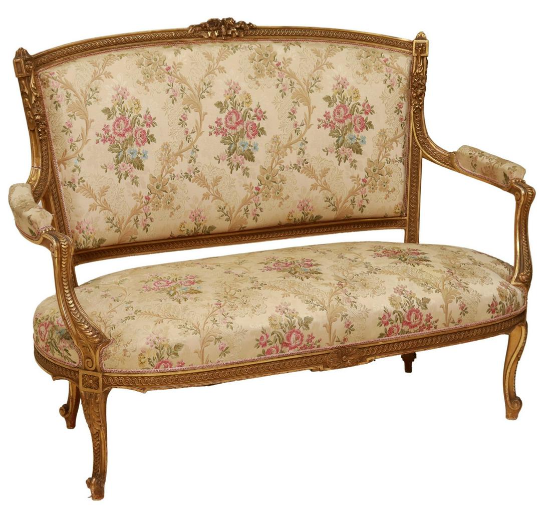FRENCH LOUIS XV STYLE GILTWOOD SALON SETTEE: French Louis XV style giltwood salon settee, 19th c., floral crest, upholstered back, arms, and seat, rising on cabriole legs, ending in whorl feet, tears to reverse backing fabric, approx 41.25"h, 54