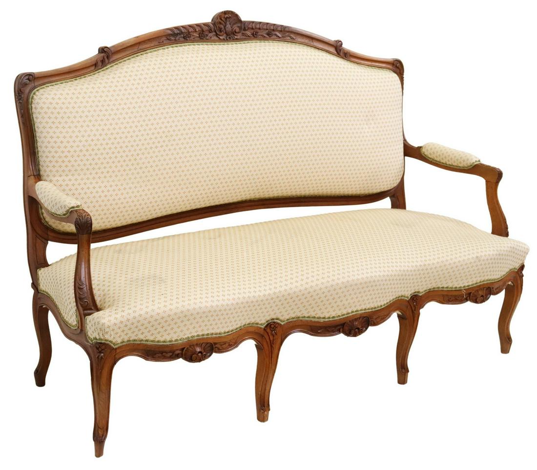 FRENCH LOUIS XV STYLE UPHOLSTERED SETTEE: French Louis XV style settee / salon sofa, 20th c., having carved rocaille crest, in a floral upholstery, with foliate handholds, above shell motif apron, rising on cabriole legs, ending on whorl feet