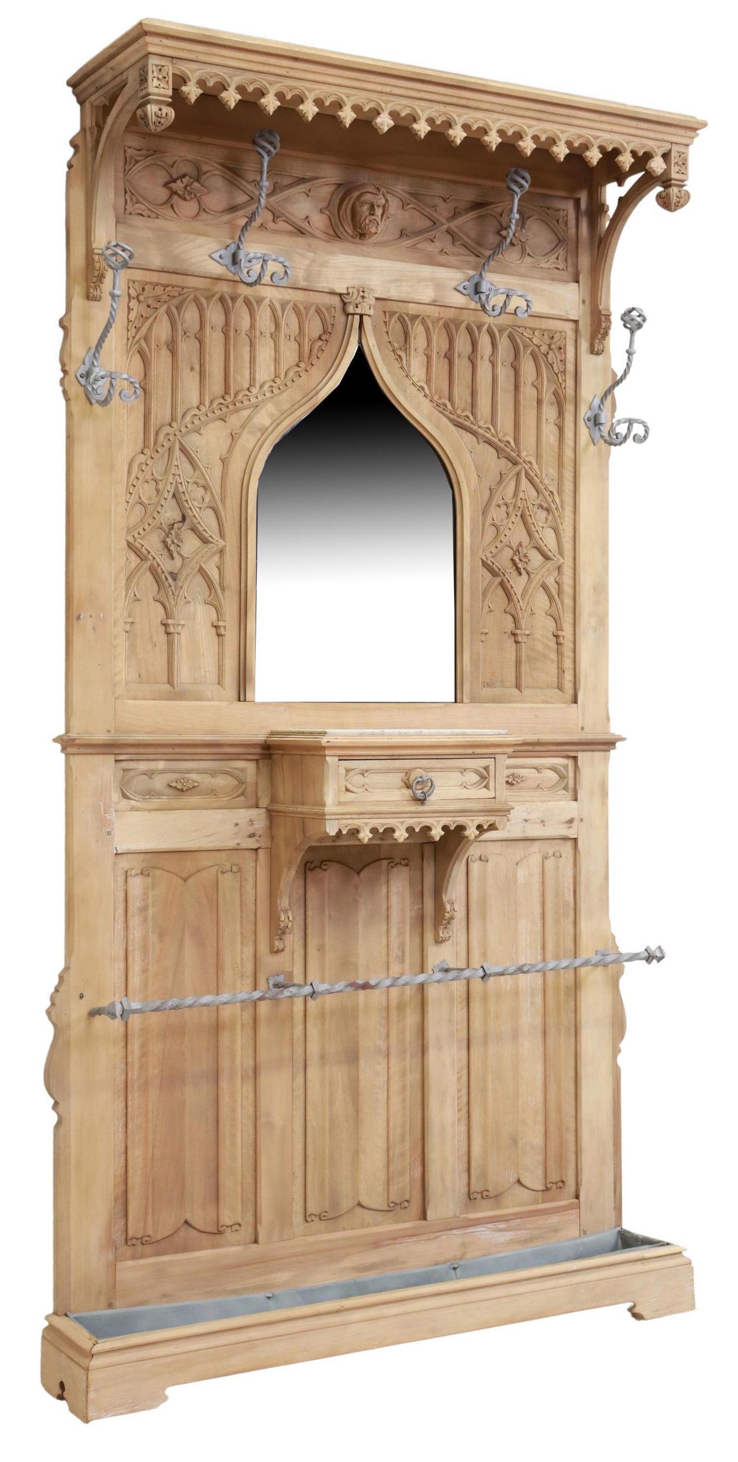FRENCH GOTHIC REVIVAL STRIPPED WALNUT HALL TREE: French Gothic Revival hall tree, late 19th c., likely stripped walnut, overhanging canopy, backboard with carved tracery, linenfold panels, four wrought iron hooks, beveled mirror plate shaped as a po
