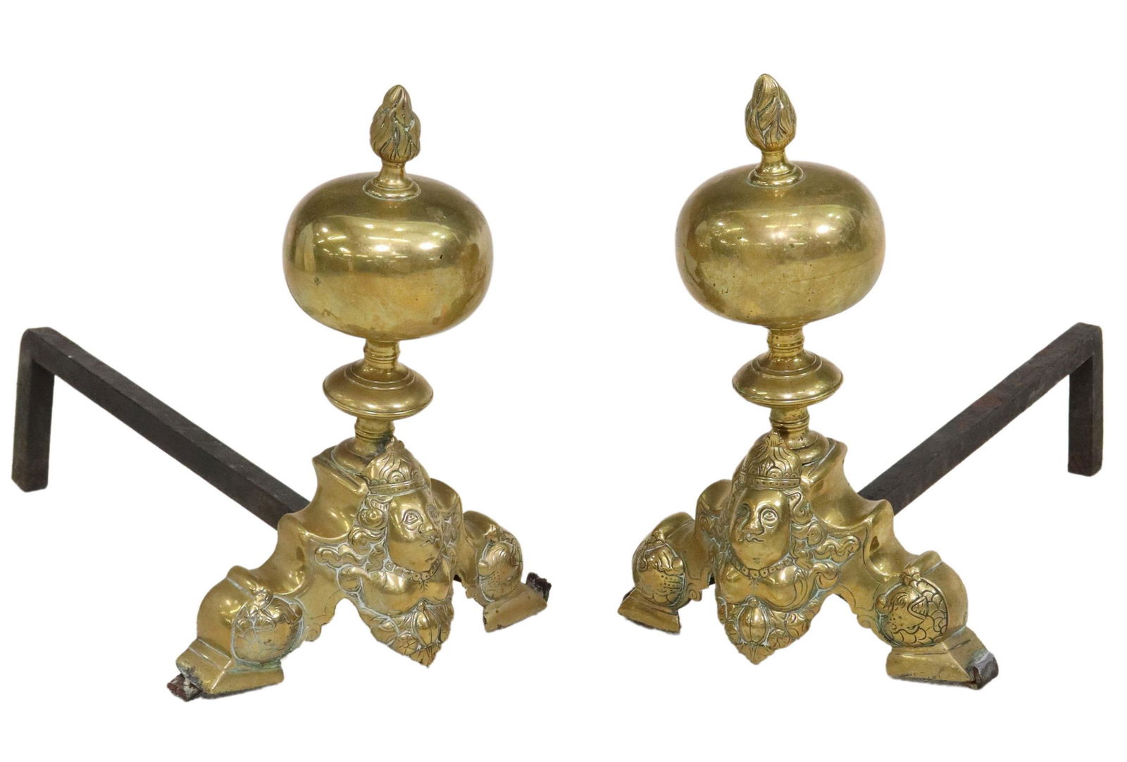 (2) BAROQUE STYLE BRASS CHENETS ANDIRONS: (pair) Baroque style brass chenets/ andirons, 19th c., ball finial, above the scroll base with mask, on a wrought iron billet bar, sit slightly askew, approx 14.75"h, 10"w, 21"d Start Price: $200.00