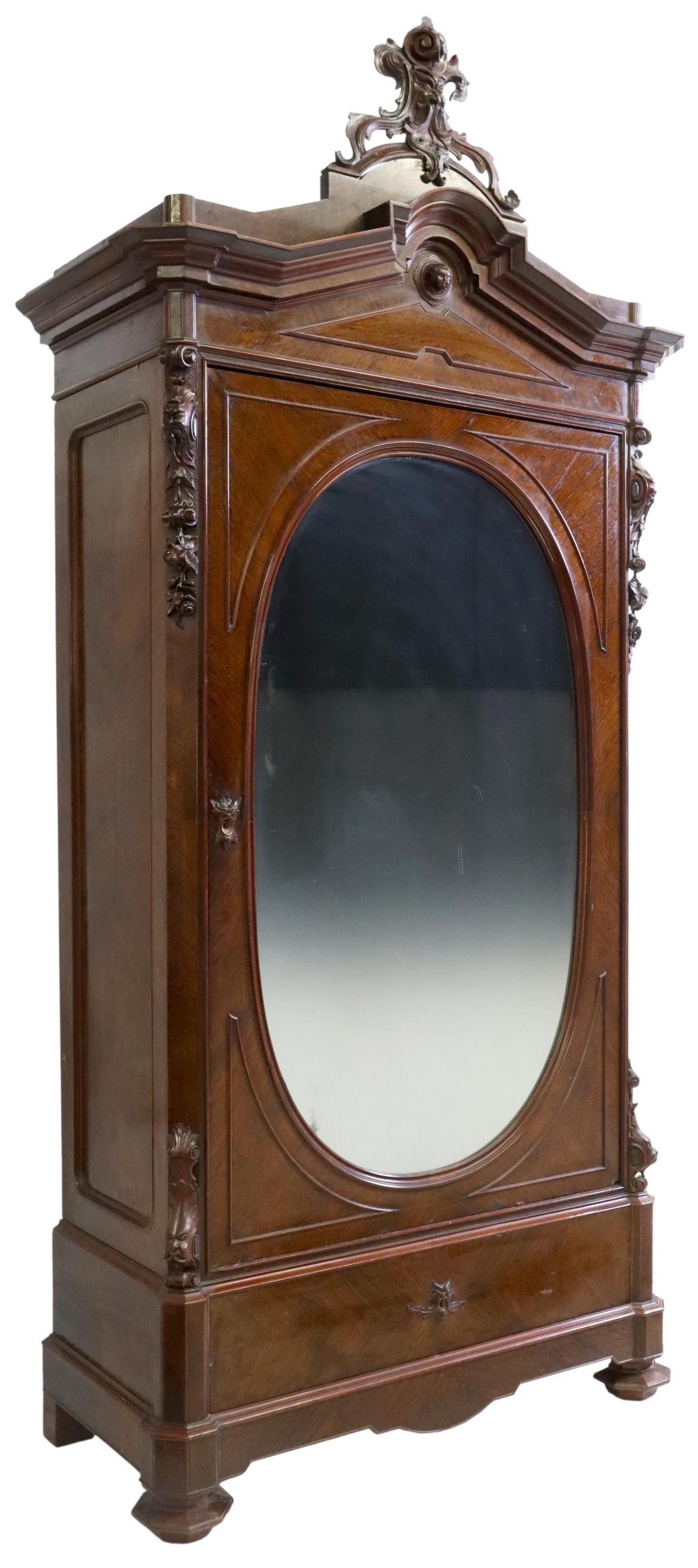 ITALIAN FOLIATE CARVED ROSEWOOD MIRRORED ARMOIRE: Italian rosewood armoire, 19th c., having foliated grotesque crest, over molded cornice, front with oval mirror plate, above lower drawer, rising on shaped feet, approx 105"h, 47"w, 22"d Start Price: 