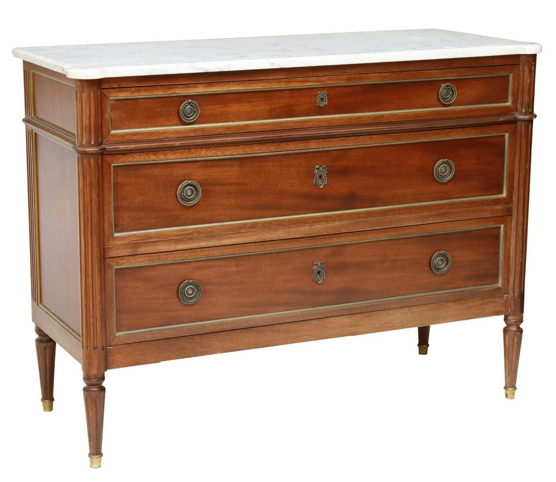FRENCH LOUIS XVI STYLE MARBLE-TOP MAHOGANY COMMODE: French Louis XVI style mahogany commode, 20th c., having marble top, over three drawers, with gilt-metal banding, flanked by fluted supports, rising on tapered legs, ending on capped feet, approx 33.5
