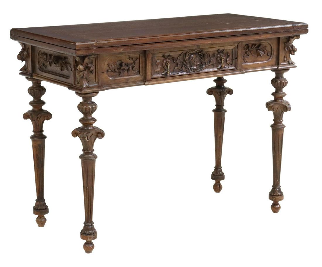 FRENCH FOLIATE CARVED FLIP-TOP FELT GAMES TABLE: French carved games table, 19th c., hinged top opening to felt-lined games table, apron carved with foliates and a male bust, having single drawer, rising on fluted and tapered legs, ending on bun fee