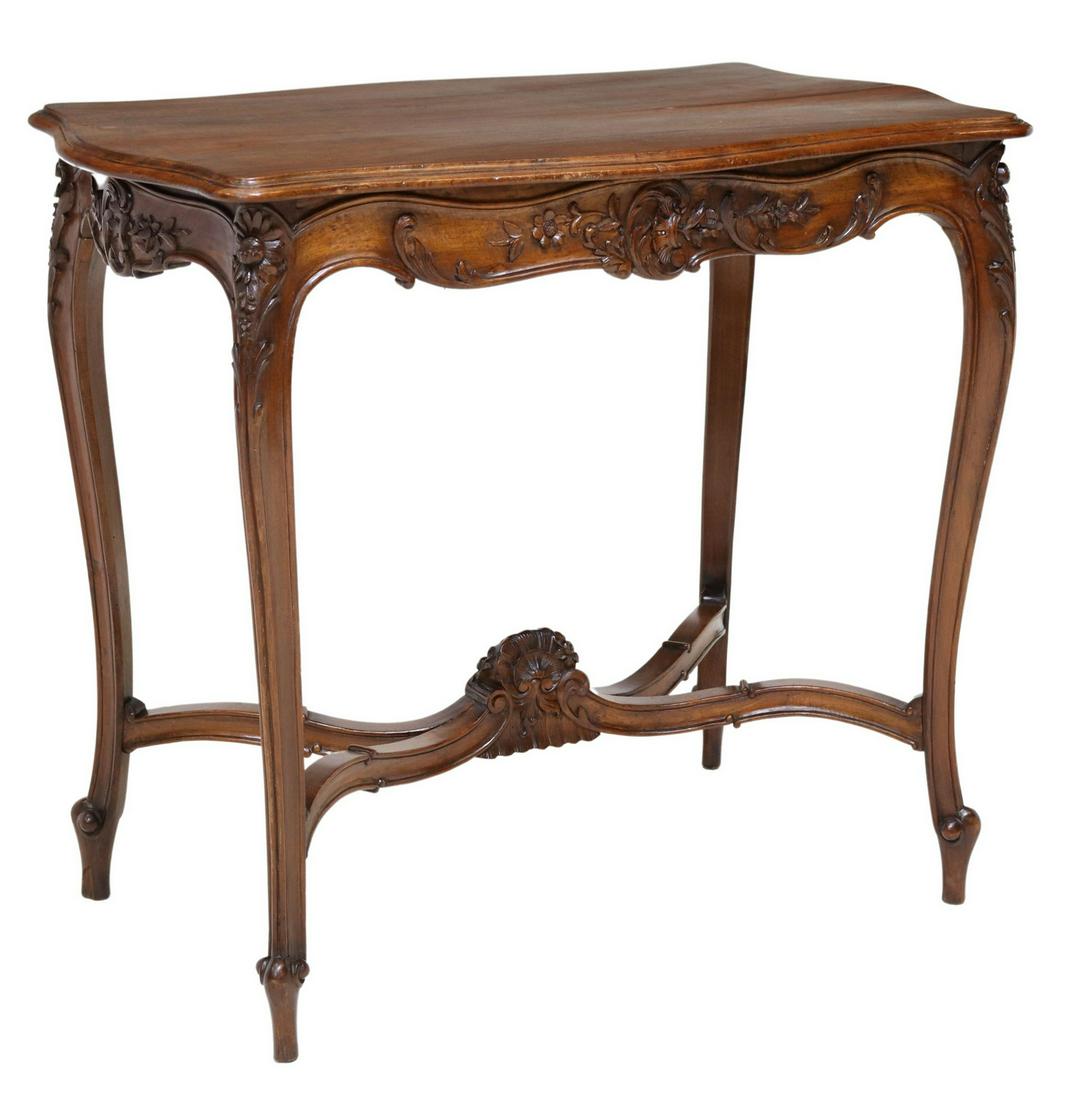 LOUIS XV STYLE CARVED WALNUT SIDE TABLE: Louis XV style walnut side table, late 19th c/ early 20thc., shaped top, over carved apron with scrolled foliates and floral motifs, rising on cabriole legs, joined by X stretcher, ending in whorl fee