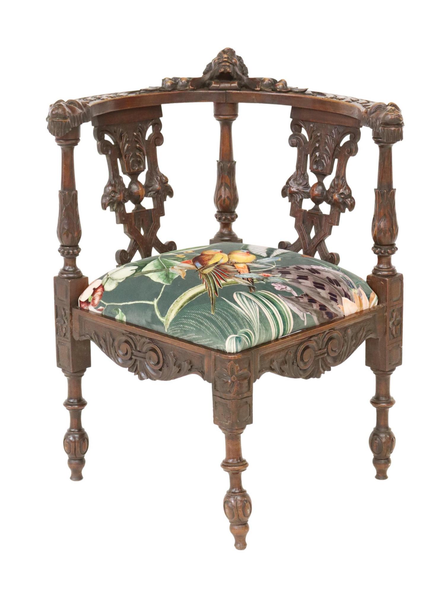 RENAISSANCE REVIVAL CARVED CORNER ARMCHAIR: Renaissance Revival carved corner armchair, late 19th/ early 20th c., having protruding mask crest, terminating in beast handholds, over pierced slat backs, tropical patterned upholstered seat cushion