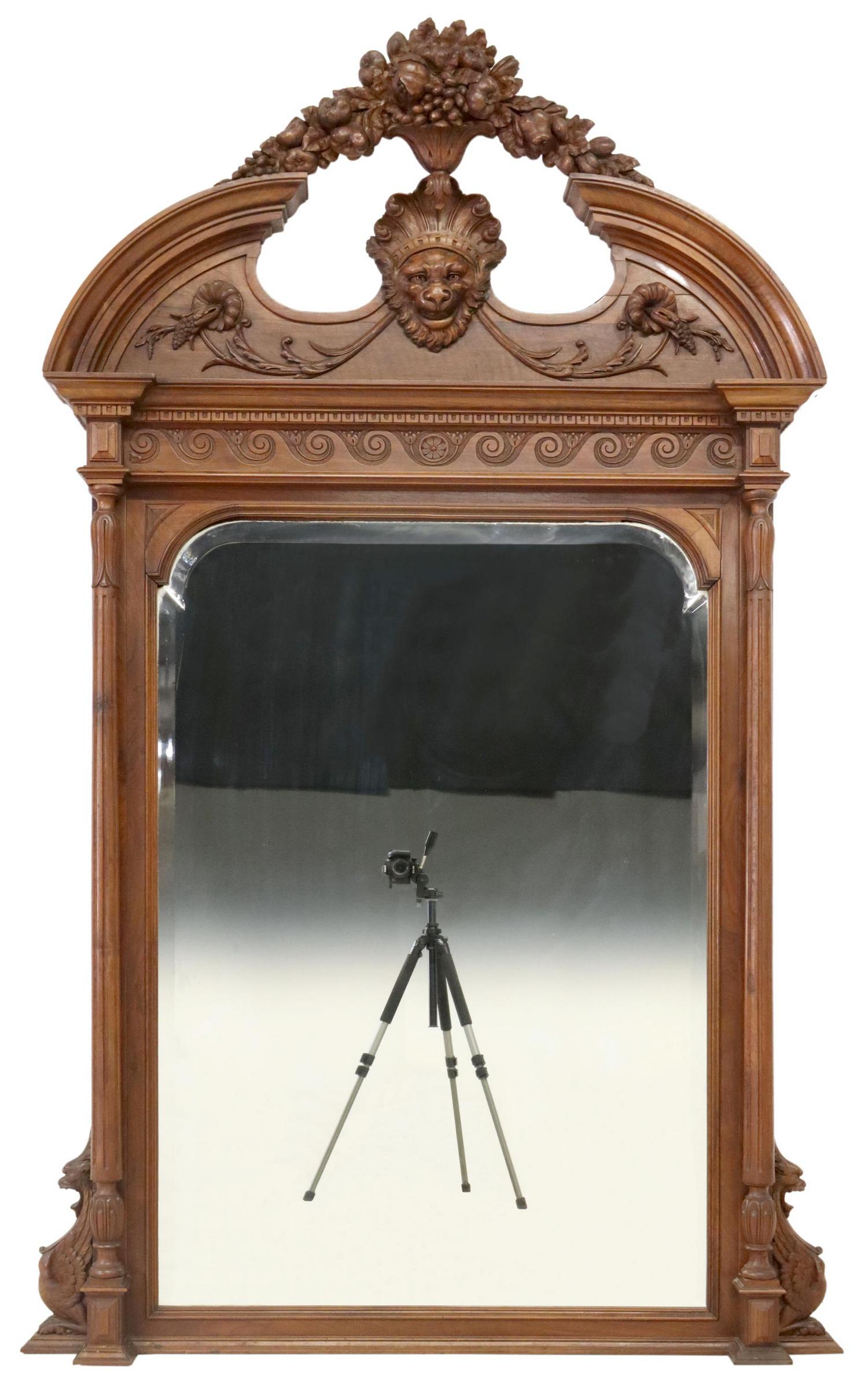RENAISSANCE REVIVAL CARVED WALNUT WALL MIRROR: Renaissance Revival carved walnut wall mirror, late 19th c., having arched pediment with fruit motifs and central lion mask, over stepped cornice with incised scroll motifs, shaped frame flanked by fl