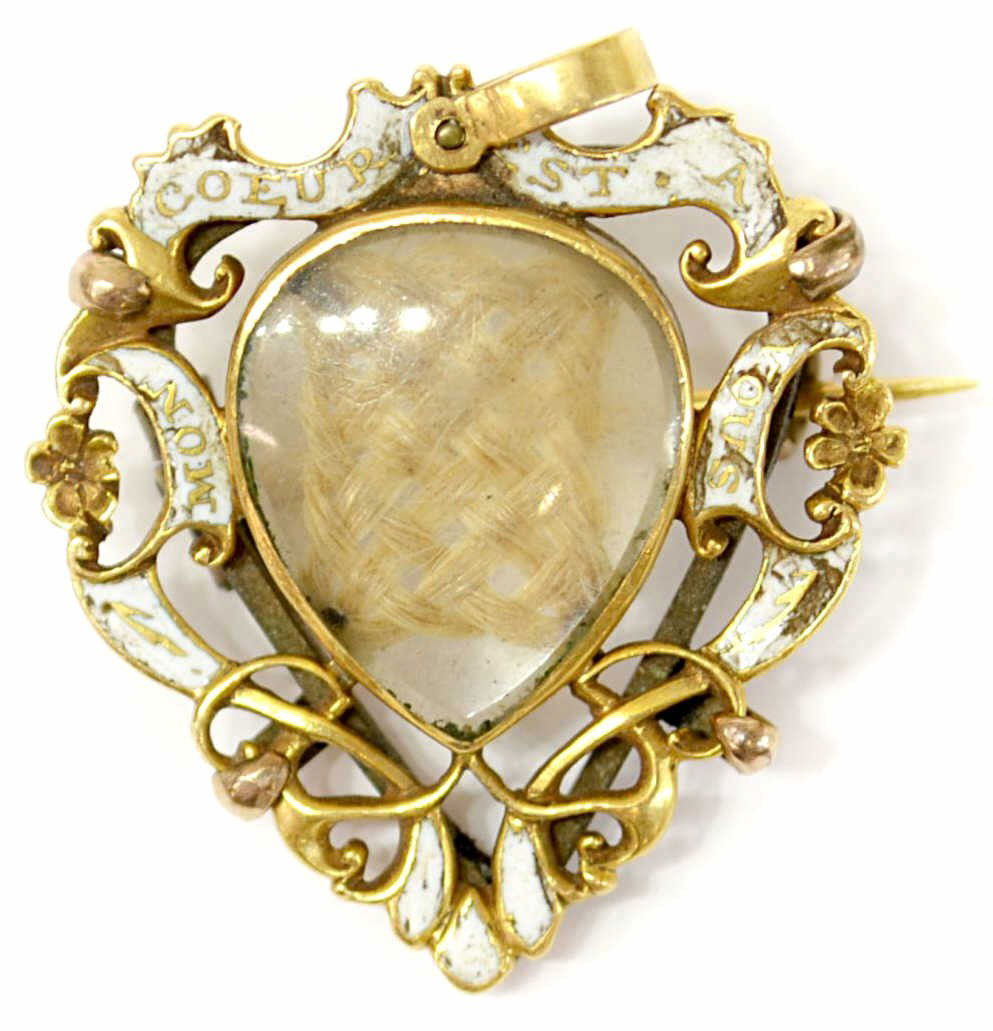 ANTIQUE 20KT GOLD SHIELD FORM ENAMEL HAIR BROOCH: Antique gold and enamel memorial hair brooch in two parts, the 20kt gold frame of shield form being the front part formed as a pendant with floral detail, white enamel banners 'Mon Coeur Est a Nous' (