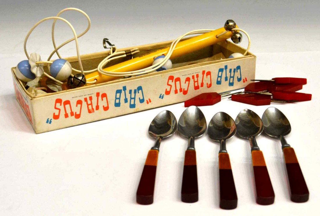 VINTAGE BAKELITE CRIB CIRCUS & KITCHEN WARE: (lot) Vintage bakelite group: (1) 'Crib Circus' baby mobile in the original box, only slight wear to finish, box: 11.25l, 4"w; (5) stainless steel spoons having bakelite handles, 6.75"l; (6) red corn 