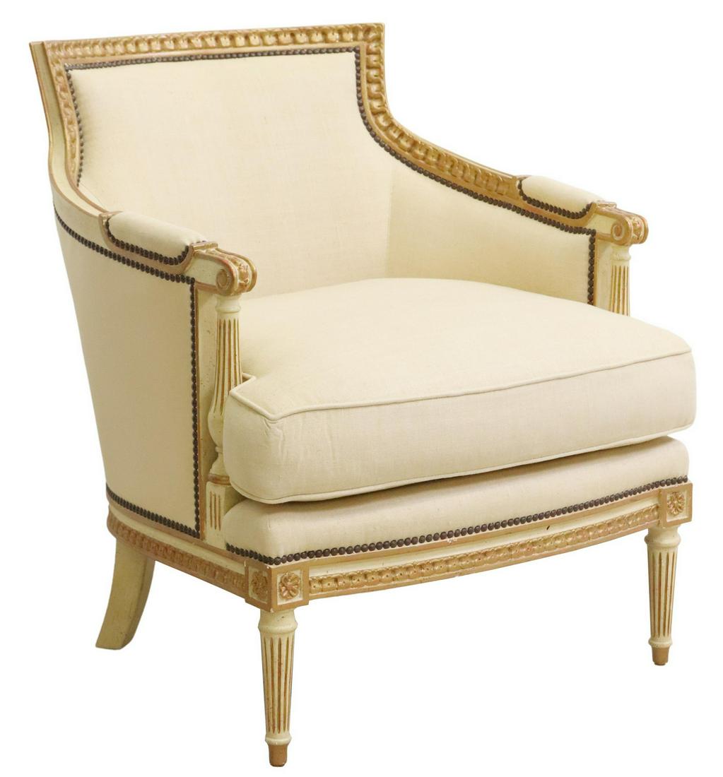 BAKER FURNITURE CO. LOUIS XVI STYLE BERGERE: Louis XVI style parcel gilt armchair, Baker Furniture Company, having carved frame with running ornamentation, in a painted and parcel gilt finish, light upholstery with nailhead trim, scrolled handho
