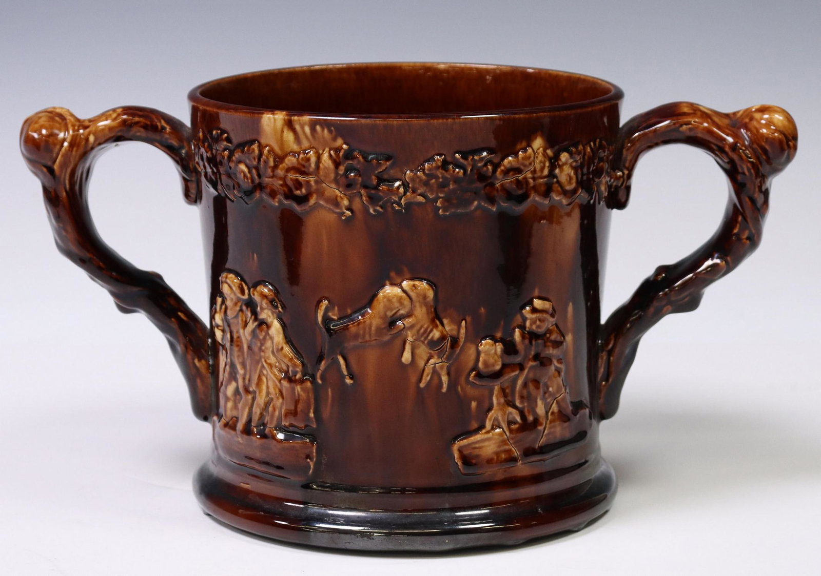 OVERSIZE ENGLISH TREACLE-GLAZED POTTERY LOVING CUP: Oversized English treacle-glazed pottery tyg/ loving cup, 19th c., with sprigged decoration, two molded frogs at interior, approx 6.75"h, 12.25"w, 7"d, 4lbs Start Price: $100.00