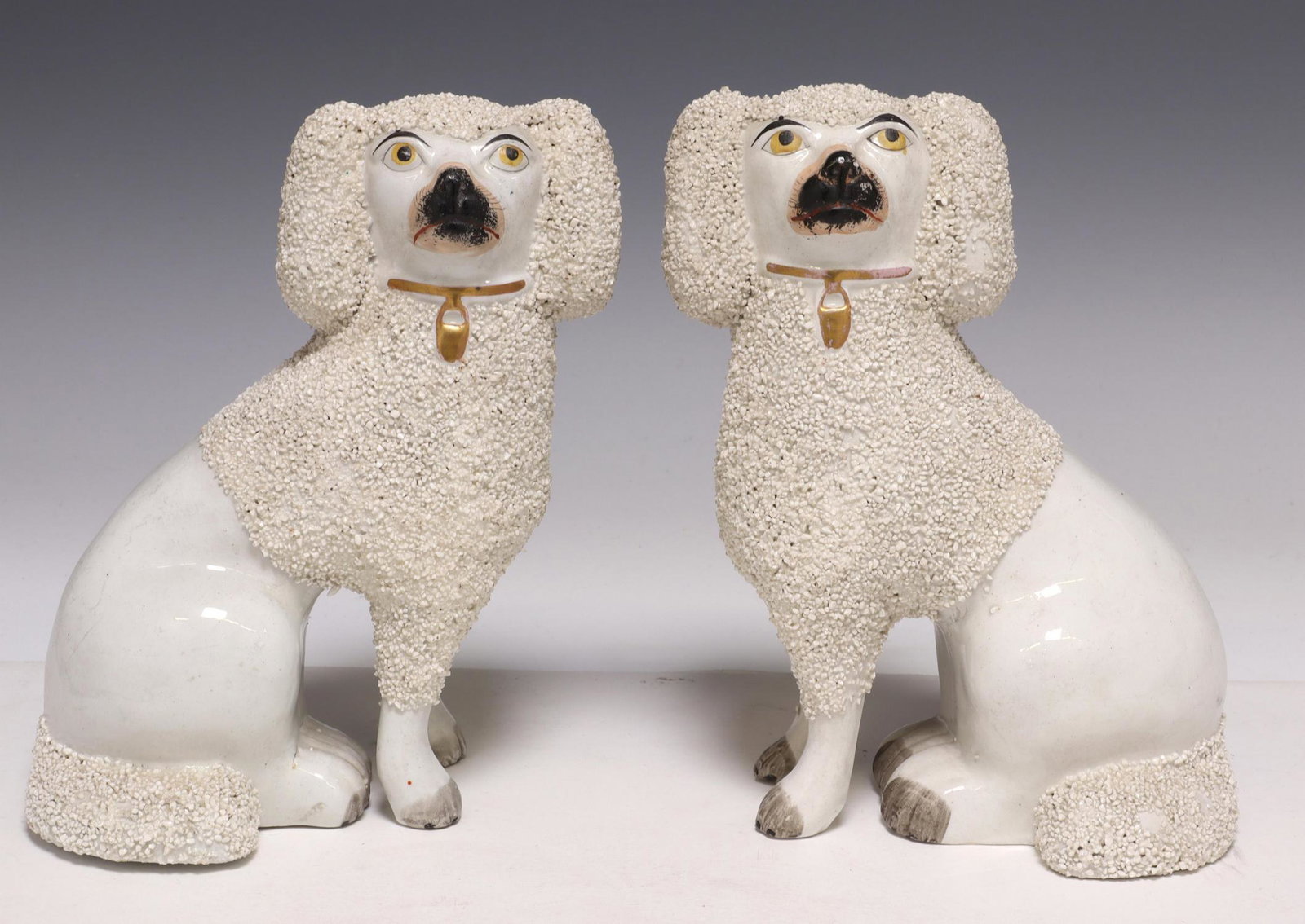(2) ENGLISH VICTORIAN STAFFORDSHIRE MANTEL DOGS: (pair) English Staffordshire mantel dogs, 19th c., in seated pose, painted features, frit textured fur at head and tail, approx 8"h, 5.5"w, 4"d; 3.25lbs total Start Price: $150.00