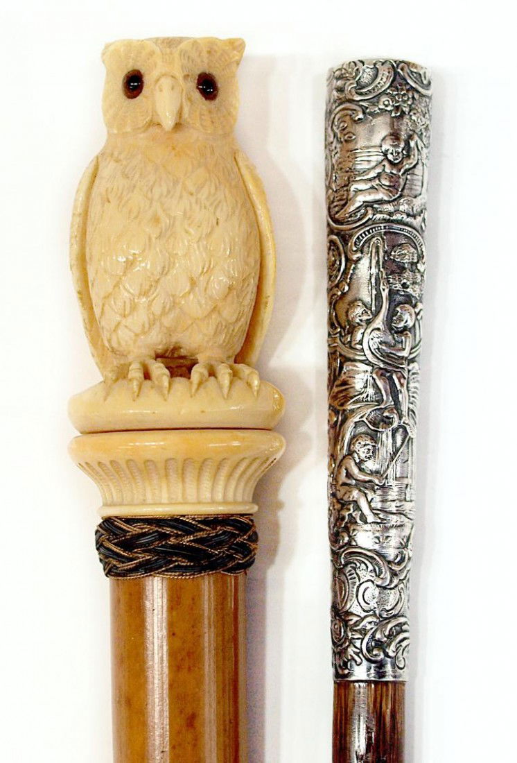 ANTIQUE IVORY OWL& REPOUSSE PUTTI SILVER CANE TOPS: **International shipping is not available for this item** (lot of 2) Antique walking cane tops: (1) wood stem surmounted by the carved ivory figure of an owl, loss to nail on one talon, ear, 10.5"; (1