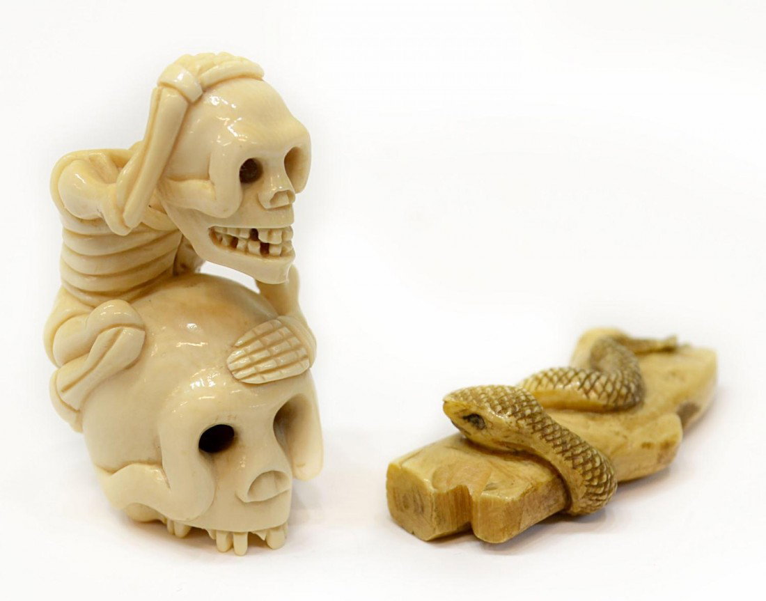 (2) JAPANESE CARVED IVORY NETSUKES, SKULL & SNAKE: **This lot will not be shipped Internationally** (lot of 2) Japanese carved ivory netsukes: (1) in the form of a snake coiled around a section of tree trunk, 1.5"l; (1) carved as a skeletal figure cli