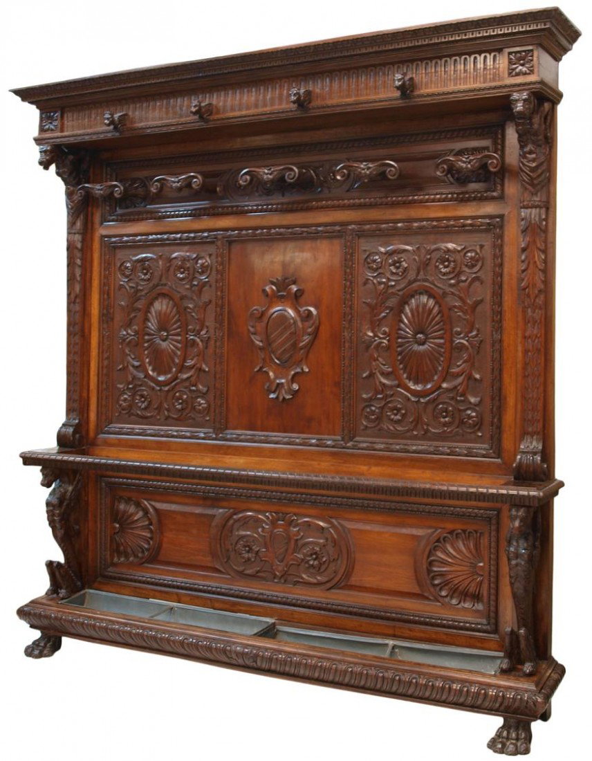 MONUMENTAL ORNATE ITALIAN WALNUT HALL TREE: Ornate Italian walnut hall tree, c. 1880, a stepped cornice with animal form hat hooks over the central foliate carved panels with carved coat hooks is flanked by grotesque mythical figures, the lower
