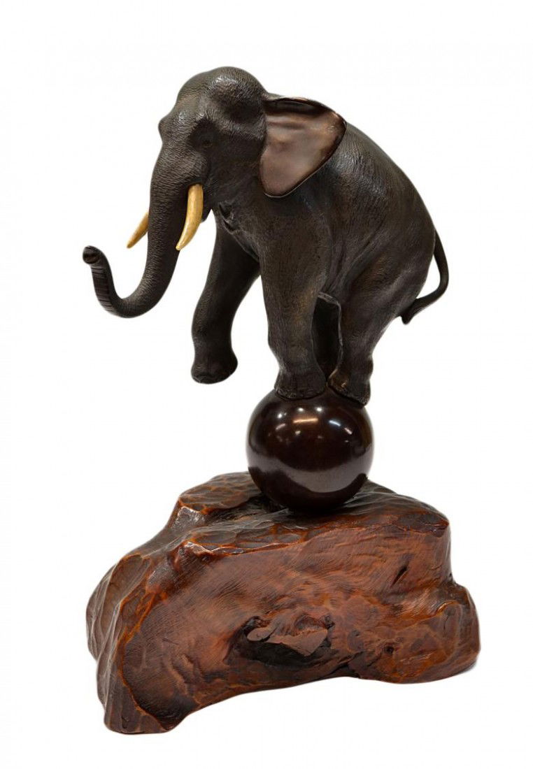 LARGE JAPANESE ELEPHANT FIGURE ON WOOD BASE: Japanese bronze figure, Meiji period, an elephant with ivory tusks posed upon a patinated ball with one foot up, characters as pictured, set in a carved wood base, elephant on ball approx: 9"h, overal