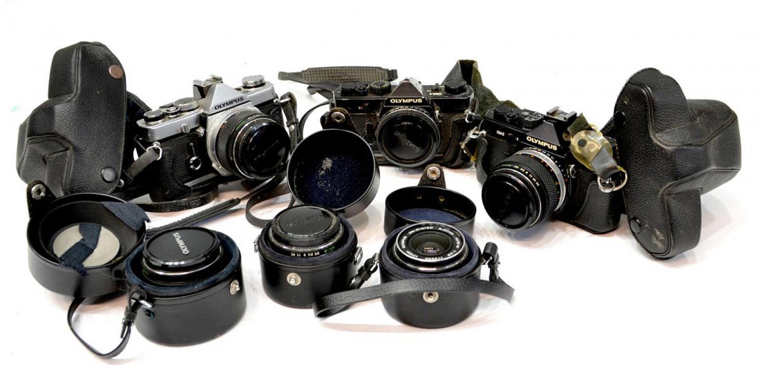 THREE OLYMPUS CAMERAS, EXTRA LENS: (1) Olympus OM-1 35mm camera; (1) Olympus OM-2 35mm camera; (1) Olympus OM-1 35mm camera body only; (3) Olympus lens, 21mm, 28mm, 35mm, total: 7.75lbs Start Price: $80.00