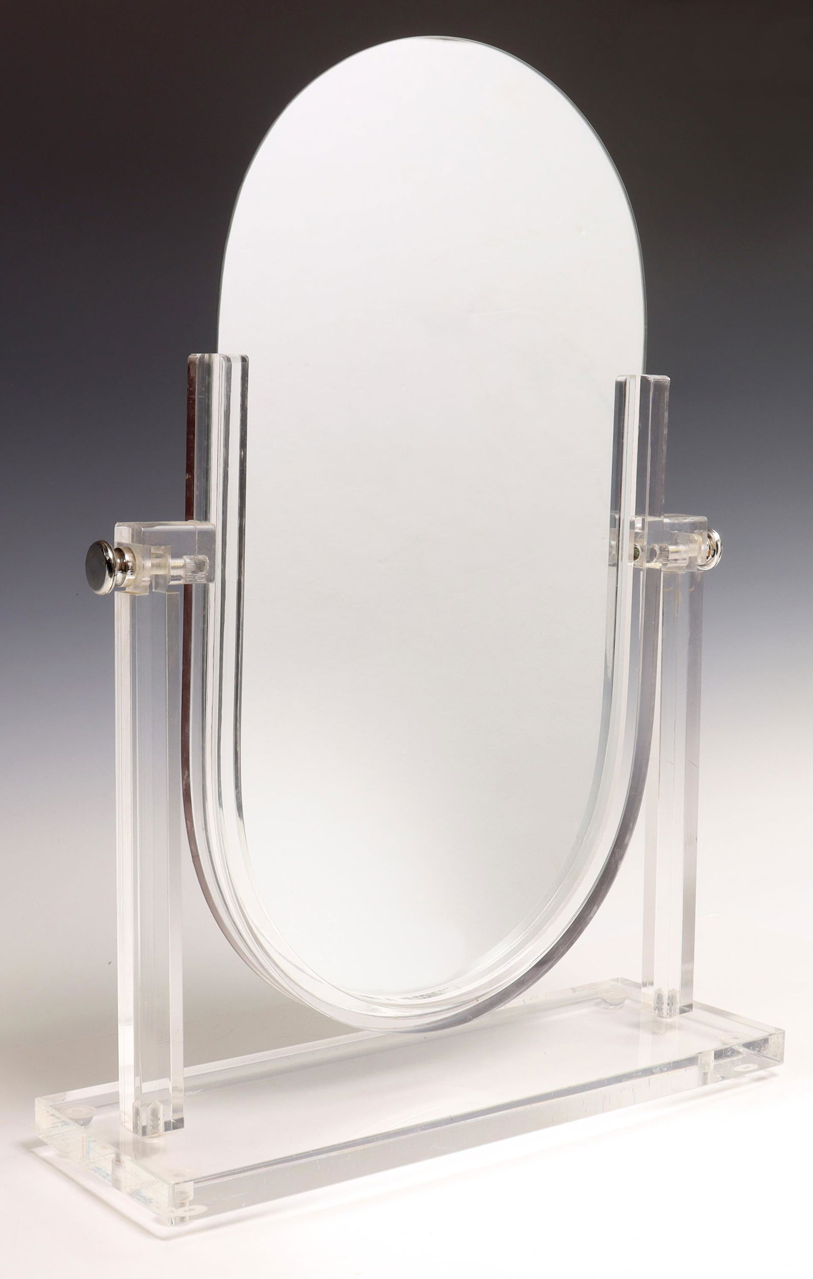 VINTAGE COLORLESS ACRYLIC TABLETOP VANITY MIRROR: Vintage vanity/ dresser mirror, oval mirror plate set in a colorless acrylic stand, approx 19.75"h, 14.25"w, 4.75"d, 4.5lbs **Provenance: Designer Courtney Blanton's CBI Studio collection, Austin, Tex